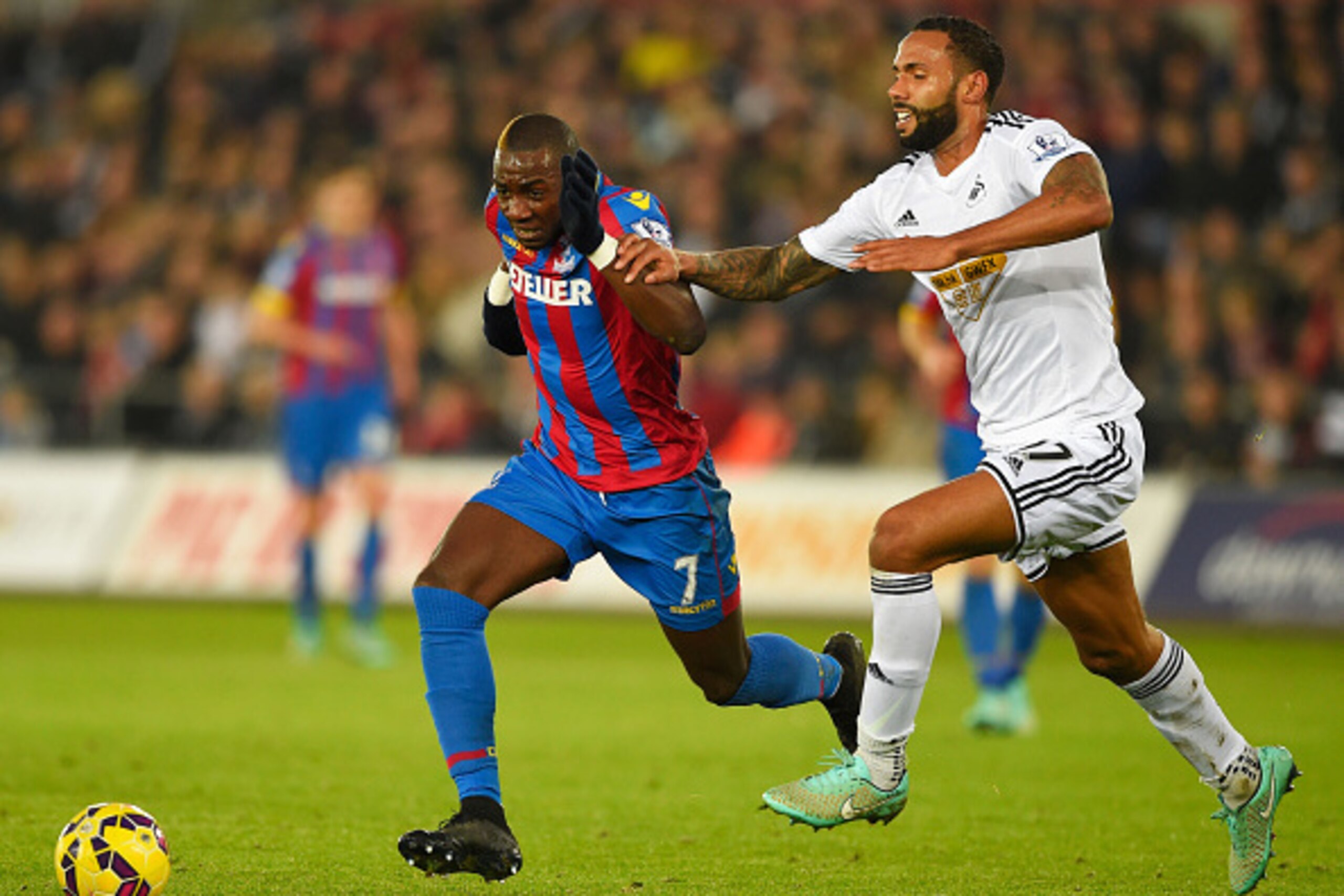 SWANSEA, WALES - NOVEMBER 29:  Yannick Bolasie of Crystal Palace takes on Kyle Bartley of Swansea City during the Barclays Premier League match between Swansea City and Crystal Palace at Liberty Stadium on November 29, 2014 in Swansea, Wales.  (Photo by M