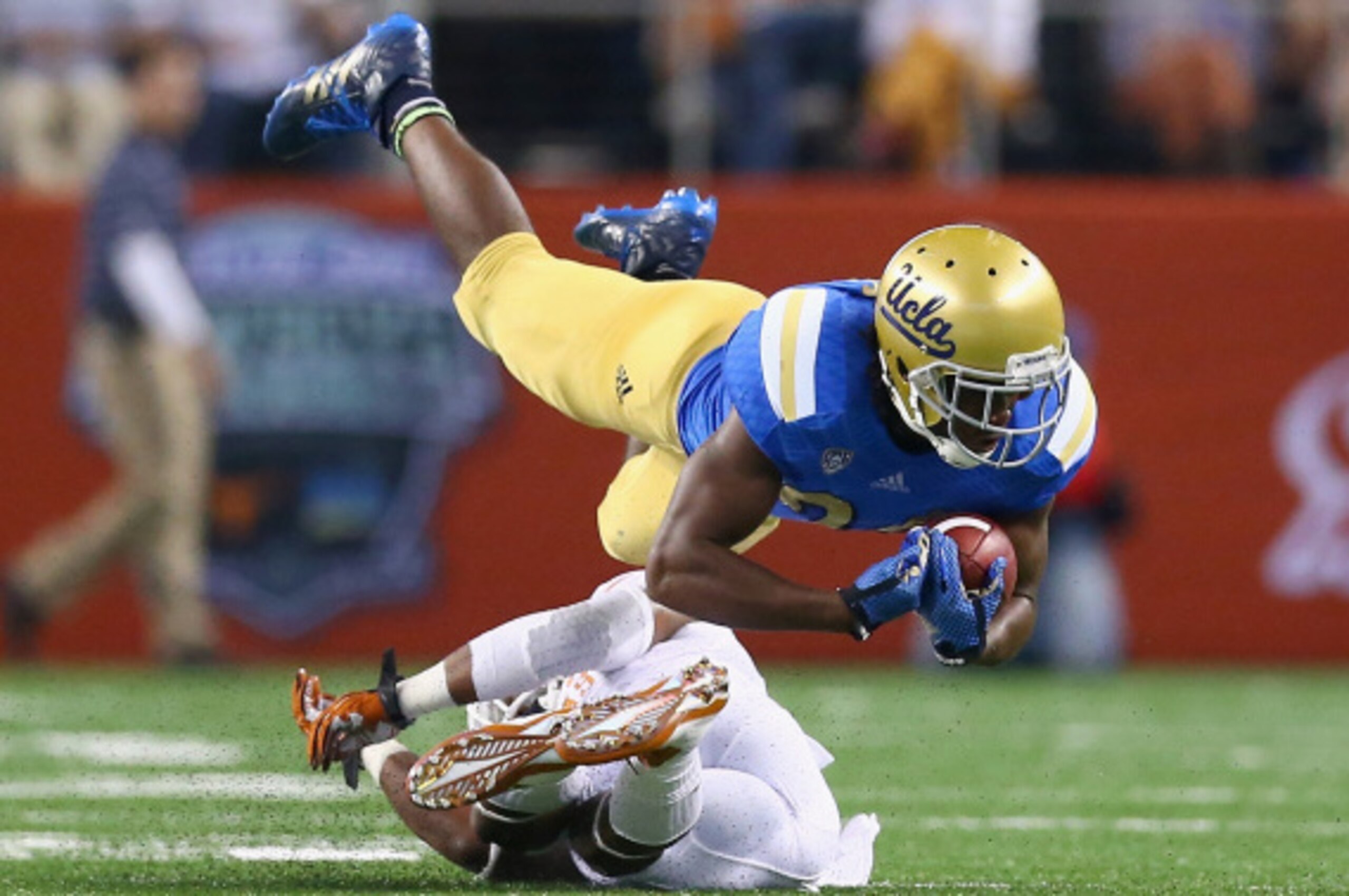 ARLINGTON, TX - SEPTEMBER 13:  Paul Perkins #24 of the UCLA Bruins is tackled by Quandre Diggs #6 of the Texas Longhorns in the first quarter at AT&T Stadium on September 13, 2014 in Arlington, Texas.  (Photo by Ronald Martinez/Getty Images)