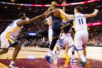 zCLEVELAND, OH - FEBRUARY 26: Harrison Barnes #40 and Klay Thompson #11 of the Golden State Warriors try to stop LeBron James #23 of the Cleveland Cavaliers during the second half at Quicken Loans Arena on February 26, 2015 in Cleveland, Ohio. The Cavalie