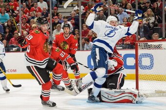CHICAGO, IL - OCTOBER 5:  Jonathan Toews #19 of the Chicago Blackhawks and Steven Stamkos #91 of the Tampa Bay Lightning chase after the puck, as Johnny Oduya #27 and Niklas Hjalmarsson #4 of the Blackhawks watch in the background, during the NHL game on 