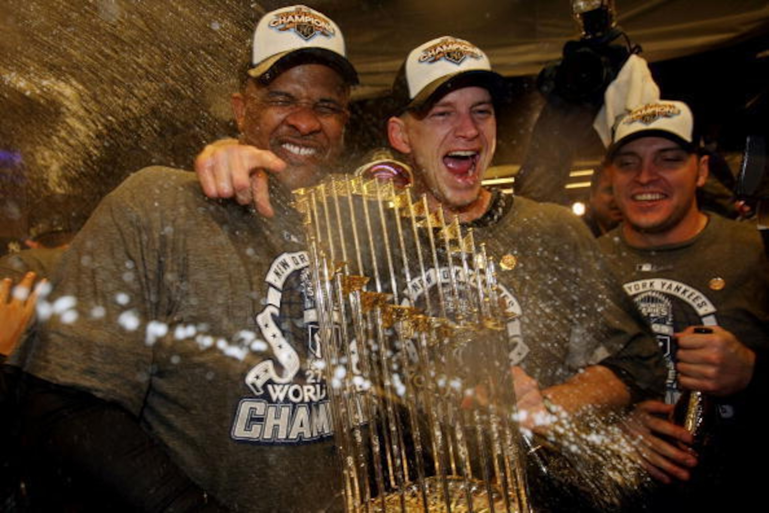 NEW YORK - NOVEMBER 04:  (L-R) C.C. Sabthia #52, A.J. Burnett #34 and Eric Hinske #14 of the New York Yankees celebrate with the trophy in the locker room after their 7-3 win against the Philadelphia Phillies in Game Six of the 2009 MLB World Series at Ya