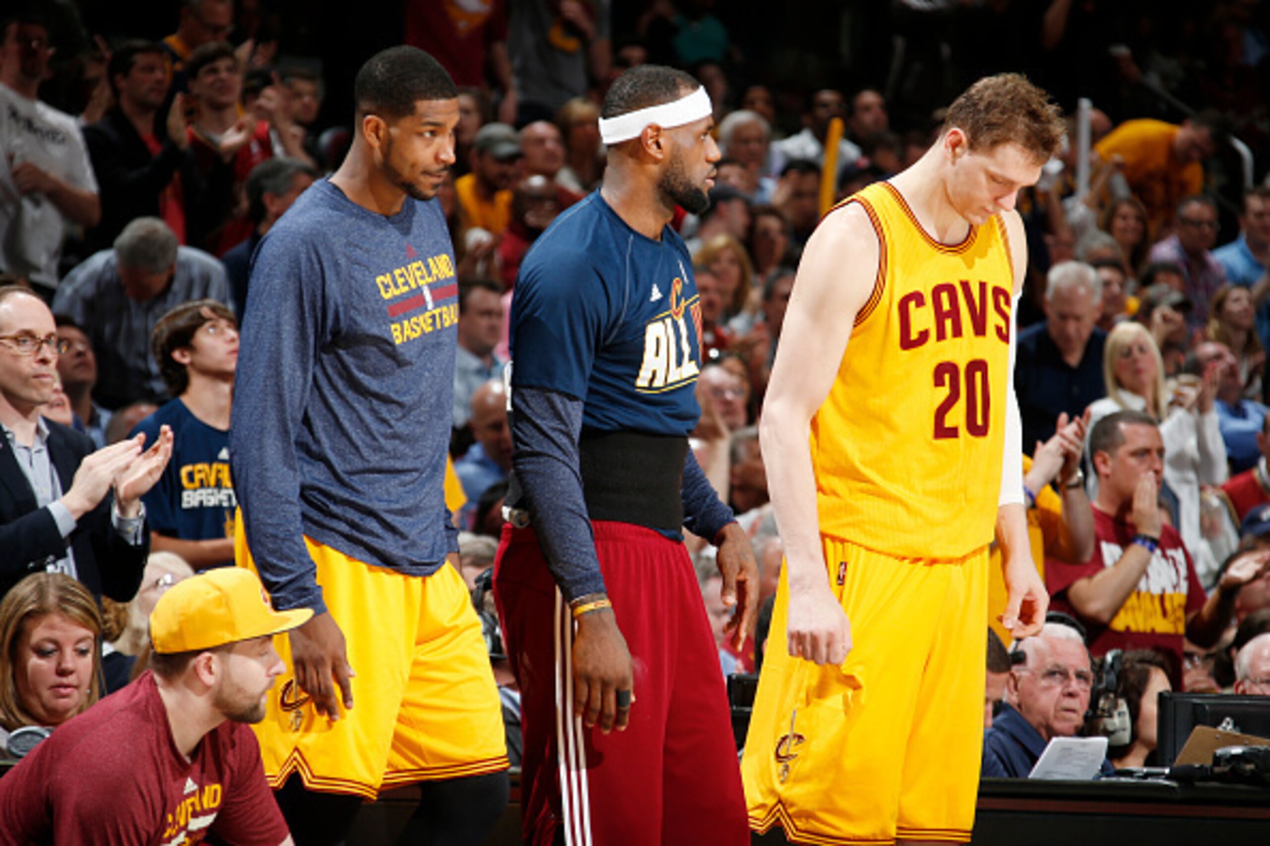 CLEVELAND, OHIO - MAY 6: Tristan Thompson #13, LeBron James #23 and Timofey Mozgov #20 of the Cleveland Cavaliers on the sidelines during Game Two of the Eastern Conference Semifinals against the Chicago Bulls during the NBA Playoffs on May 6, 2015 at Qui