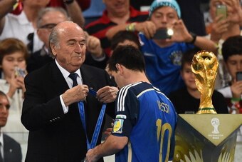 RIO DE JANEIRO, BRAZIL - JULY 13:   Lionel Messi of Argentina receives the second place medal  from FIFA President Joseph S. Blatter during the award ceremony after the 2014 FIFA World Cup Brazil Final match between Germany and Argentina at Maracana on Ju