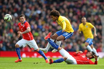 LONDON, ENGLAND - MARCH 29:  Willian of Brazil is tackled by Gonzalo Jara of Chile during the international friendly match between Brazil and Chile at the Emirates Stadium on March 29, 2015 in London, England.  (Photo by Paul Gilham/Getty Images)