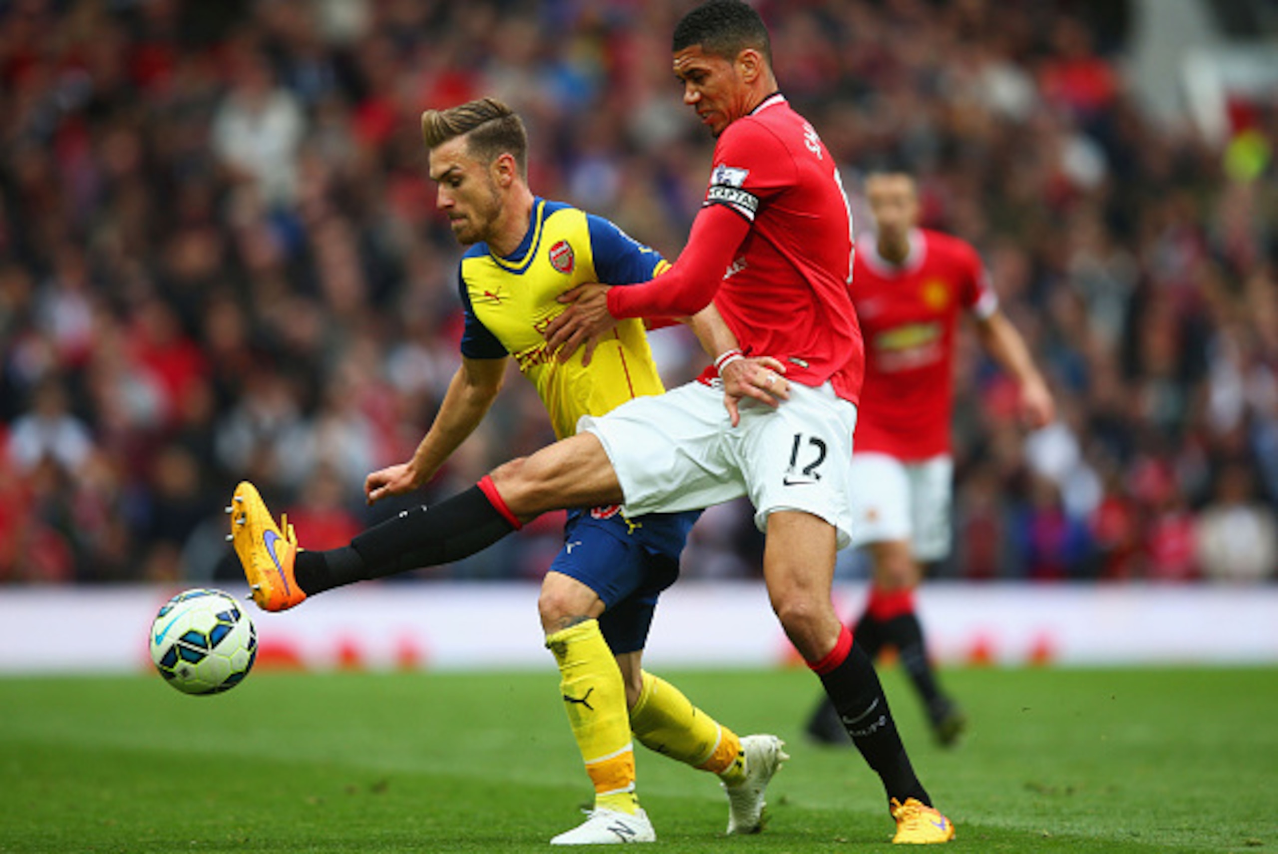 MANCHESTER, ENGLAND - MAY 17:  Aaron Ramsey of Arsenal holds off Chris Smalling of Manchester United during the Barclays Premier League match between Manchester United and Arsenal at Old Trafford on May 17, 2015 in Manchester, England.  (Photo by Clive Ro