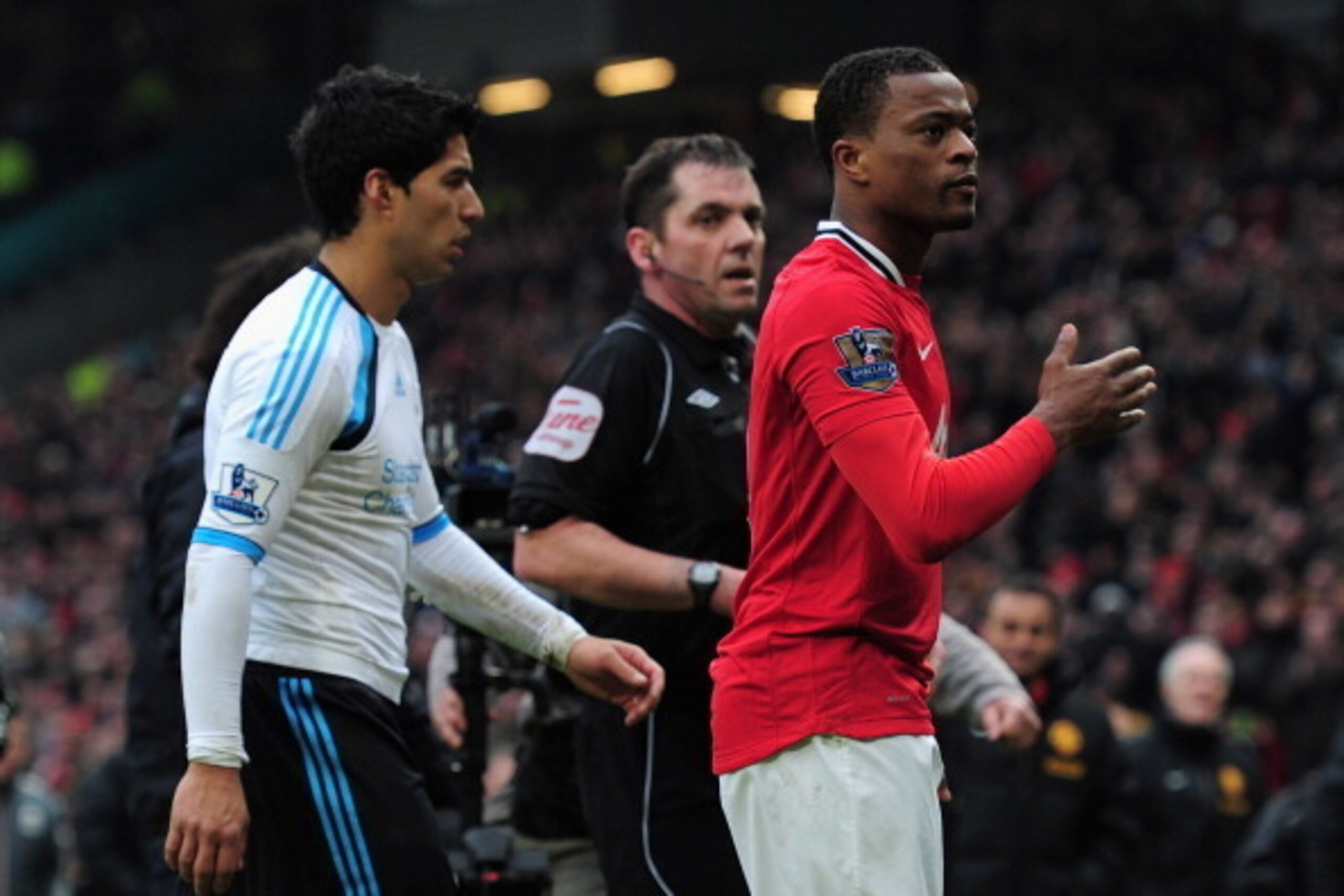 MANCHESTER, ENGLAND - FEBRUARY 11:  Patrice Evra of Manchester United celebrates victory as he walks off with Luis Suarez of Liverpool during the Barclays Premier League match between Manchester United and Liverpool at Old Trafford on February 11, 2012 in