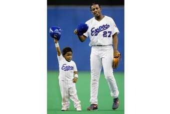 Vladimir Guerrero Jr. and father Vladimir Sr. tip their caps to the crowd after a game in 2002.