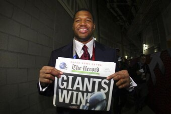 GLENDALE, AZ - FEBRUARY 03:  Defensive end Michael Strahan #92 of the New York Giants holds a copy of the Bergen Record with the headline 'GIANTS WIN!' after the Giants defeated the New England Patriots 17-14 during Super Bowl XLII on February 3, 2008 at 