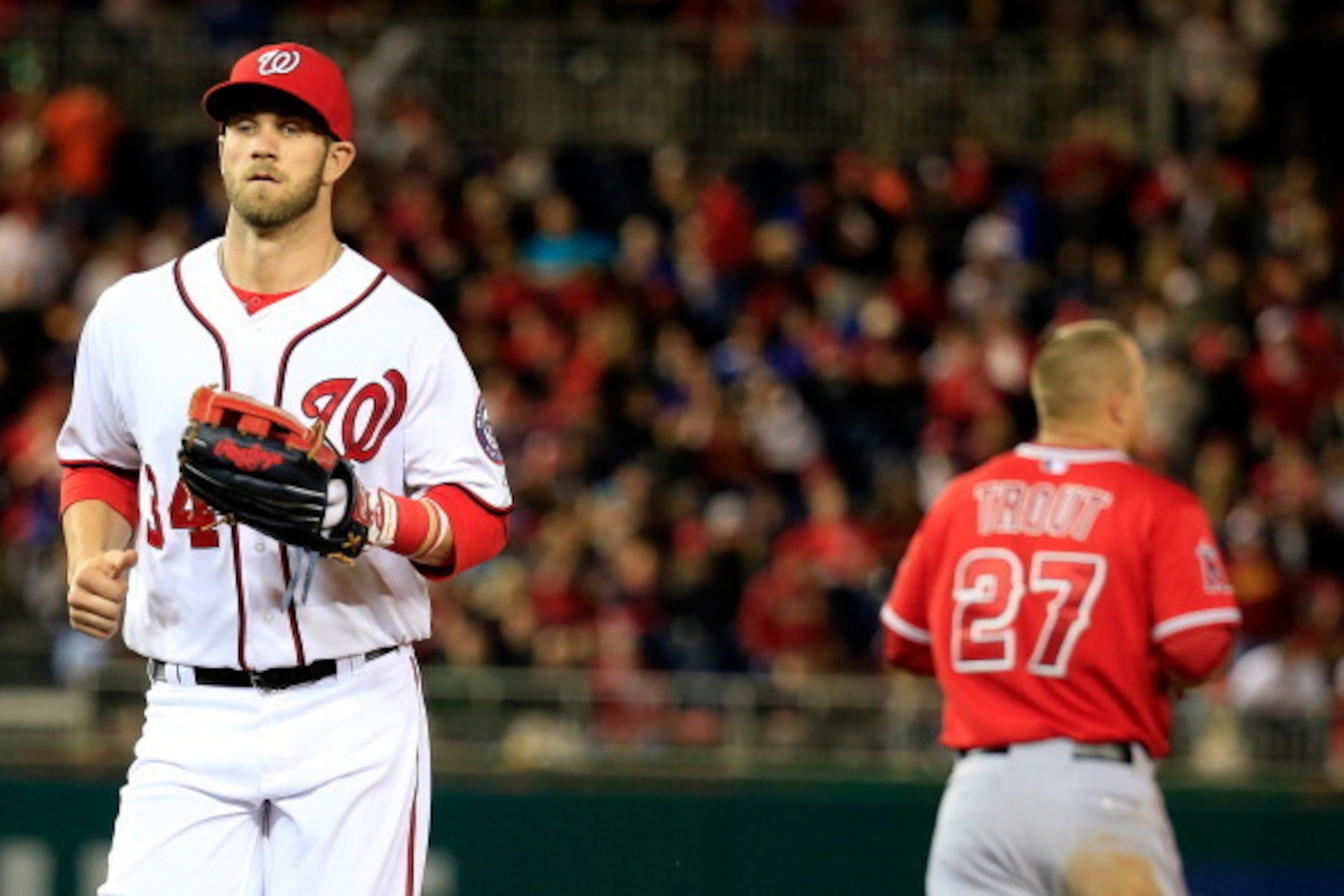 WASHINGTON, DC - APRIL 21: Bryce Harper #34 of the Washington Nationals jogs past Mike Trout #27 of the Los Angeles Angels after Trout lined out for the third out of the seventh inning of the Angels 4-2 winat Nationals Park on April 21, 2014 in Washington