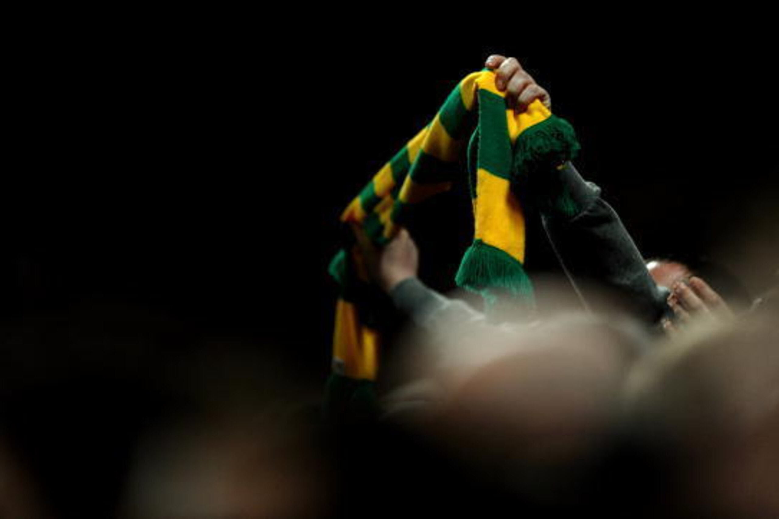 MANCHESTER, ENGLAND - MARCH 10: A Manchester United fan holds a green and gold scarf during the UEFA Champions League First Knockout Round, second leg match between Manchester United and AC Milan at Old Trafford on March 10, 2010 in Manchester, England. (
