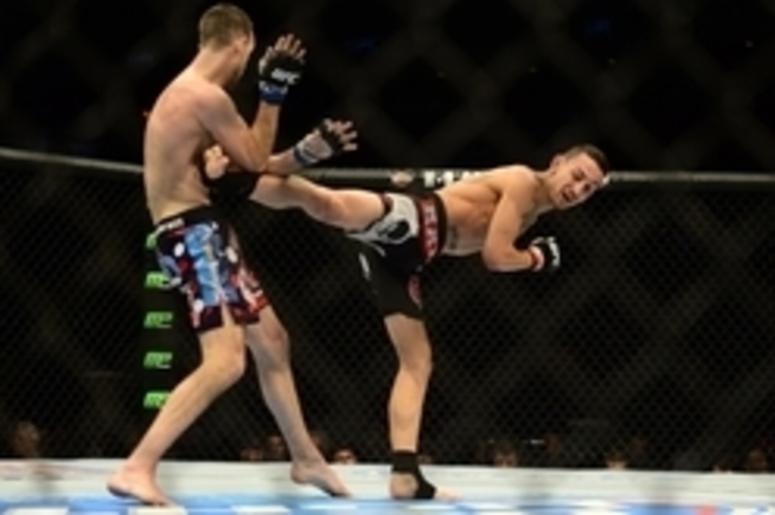 Feb 14, 2015; Broomfield, CO, USA; Cole Miller (blue) takes a kick from Max Holloway (red) during the UFC Fight Night at the 1stBANK Center. Mandatory Credit: Ron Chenoy-USA TODAY Sports