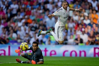MADRID, SPAIN - OCTOBER 25: Karim Benzema (R) of Real Madrid CF falls after clashing with goalkeeper Claudio Bravo (L) of FC Barcelona during the La Liga match between Real Madrid CF and FC Barcelona at Estadio Santiago Bernabeu on October 25, 2014 in Mad