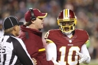Dec 20, 2014; Landover, MD, USA; Washington Redskins head coach Jay Gruden (C) talks to Redskins quarterback Robert Griffin III (10) in the second half against the Philadelphia Eagles at FedEx Field. The Redskins won 27-24. Mandatory Credit: Geoff Burke-U