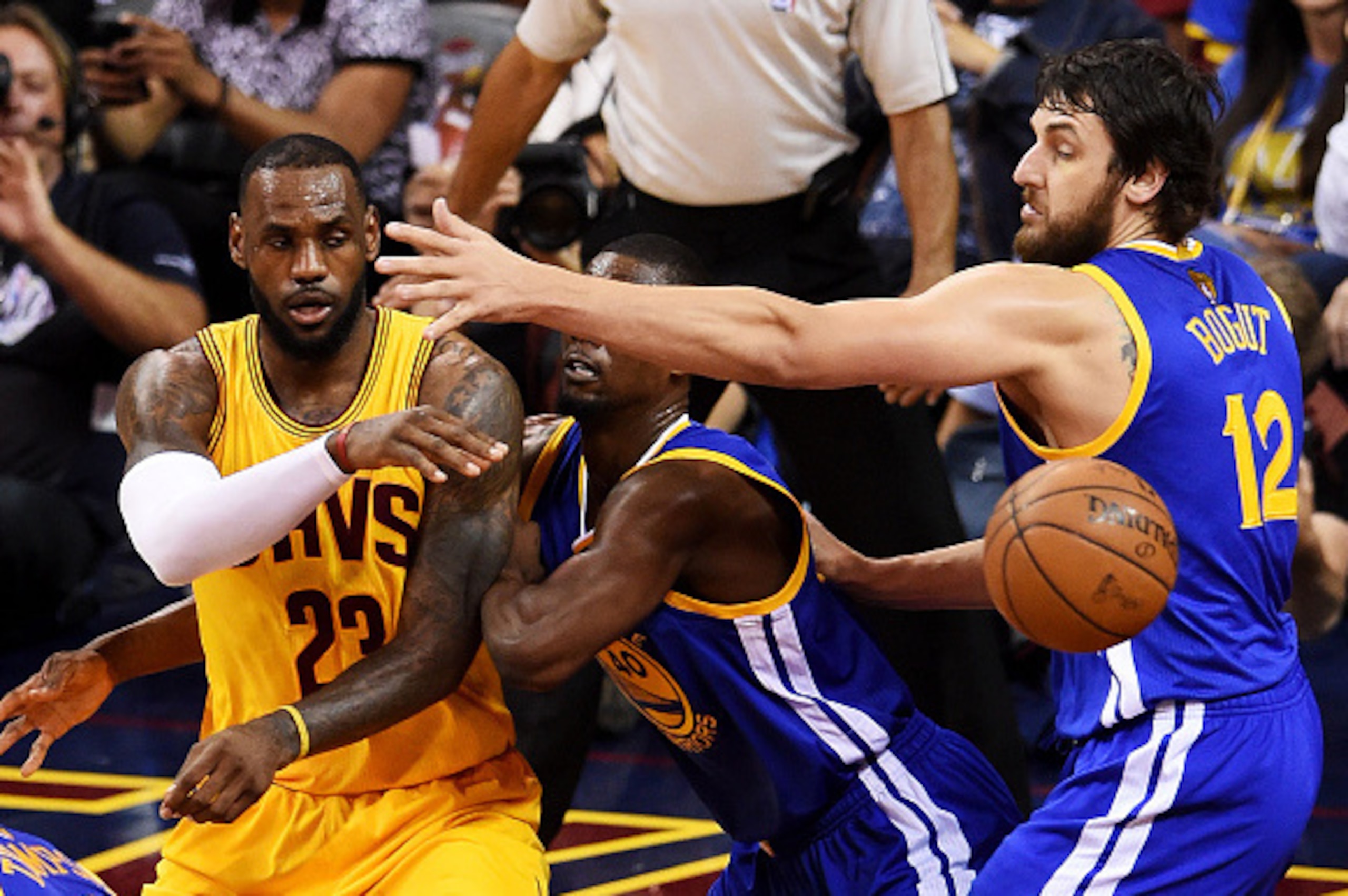 CLEVELAND, OH - JUNE 09:  LeBron James #23 of the Cleveland Cavaliers passes around Harrison Barnes #40 and Andrew Bogut #12 of the Golden State Warriors in the third quarter during Game Three of the 2015 NBA Finals at Quicken Loans Arena on June 9, 2015 