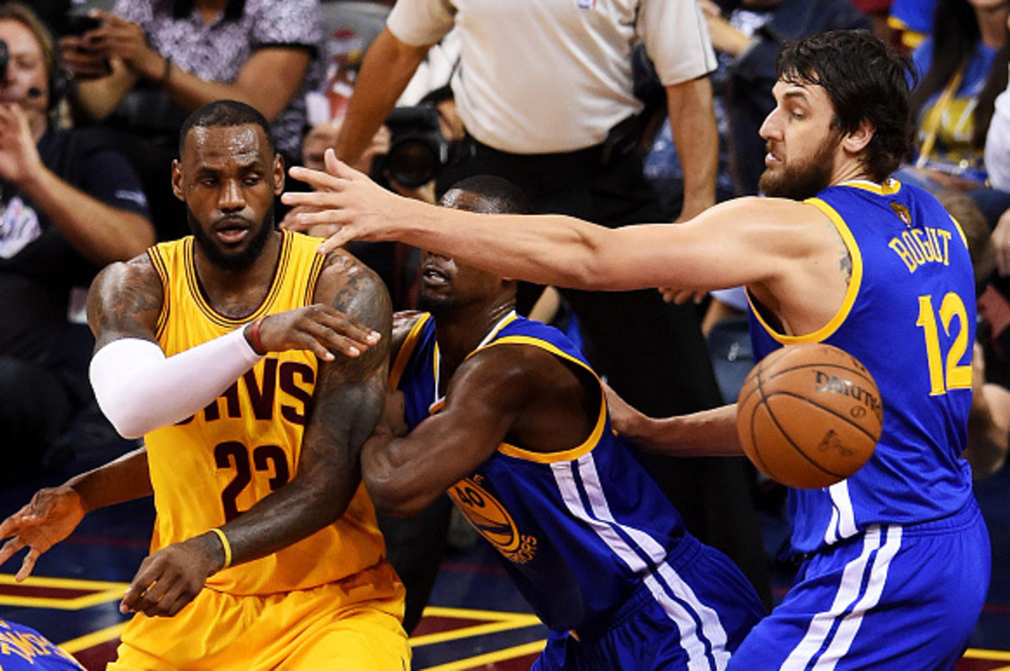 CLEVELAND, OH - JUNE 09:  LeBron James #23 of the Cleveland Cavaliers passes around Harrison Barnes #40 and Andrew Bogut #12 of the Golden State Warriors in the third quarter during Game Three of the 2015 NBA Finals at Quicken Loans Arena on June 9, 2015 