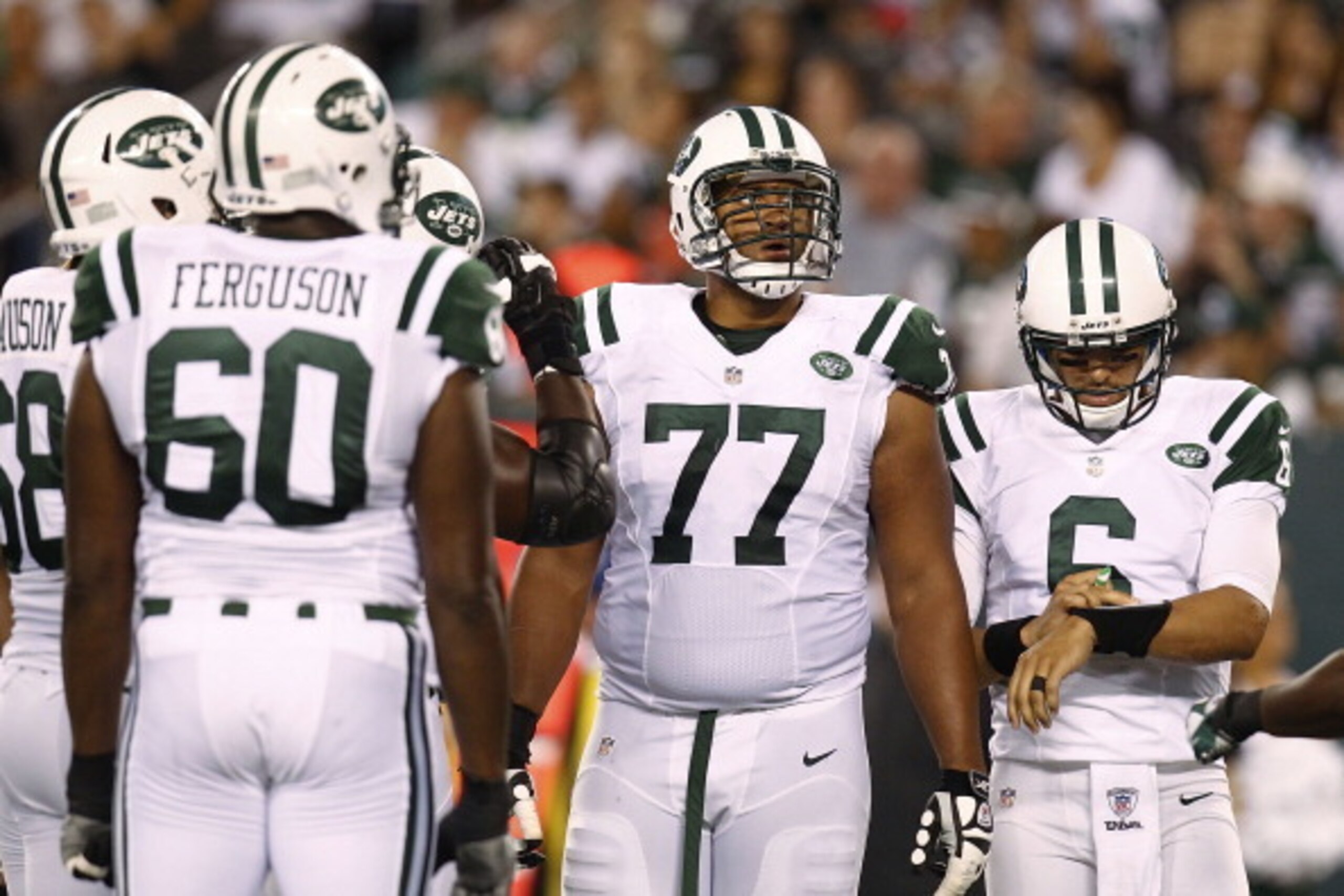 EAST RUTHERFORD, NJ - AUGUST 26:  Austin Howard #77 of the New York Jets and  Mark Sanchez #6 of the New York Jets stand during a huddle against the Carolina Panthers during their preseason game at MetLife Stadium on August 26, 2012 in East Rutherford, Ne