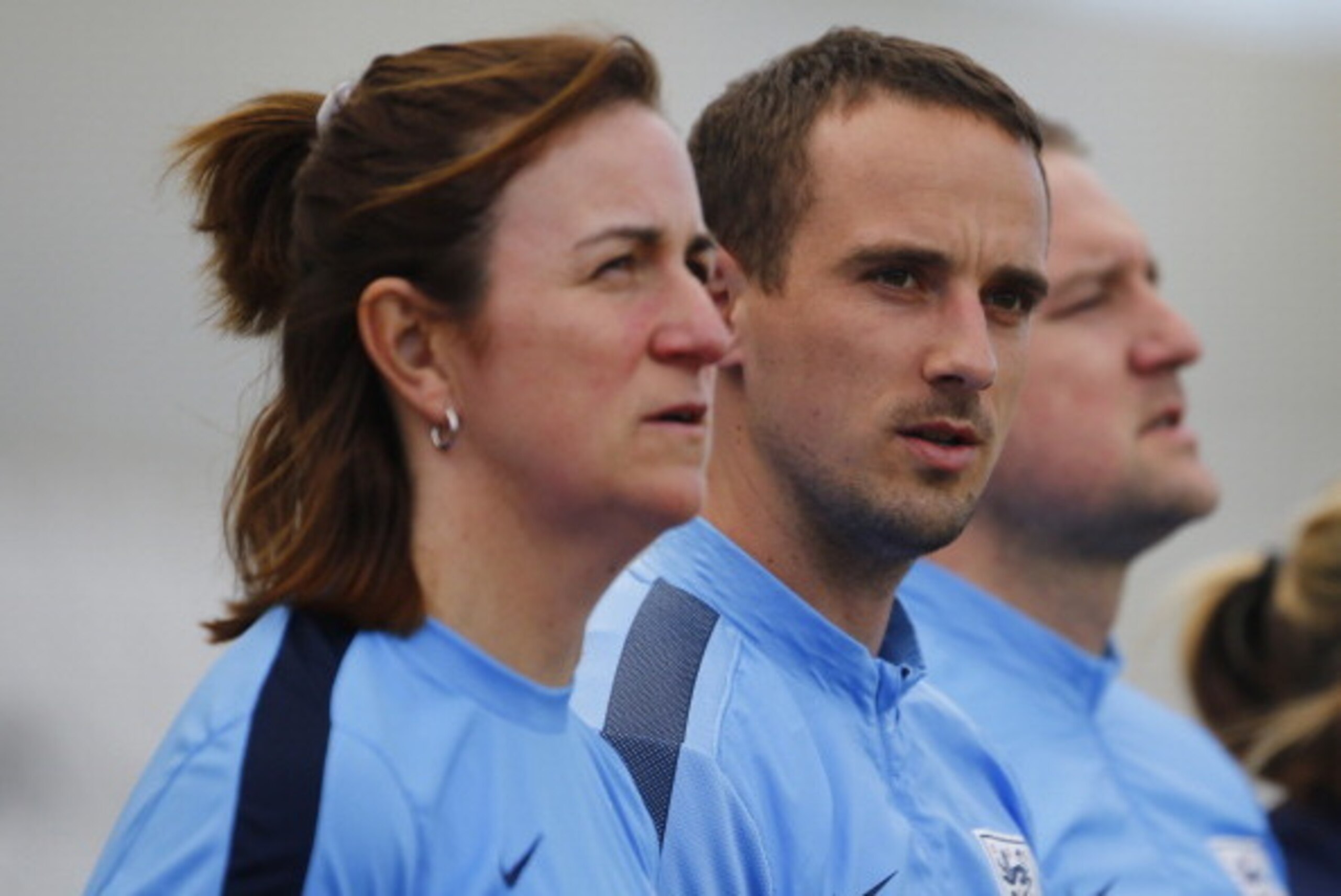 NICOSIA, CYPRUS - MARCH 10:  Head Coach Mark Sampson (C), Assistant coach Marieanne Spacey, and Goalkeeper coach Lee Kendal of England sing the national anthem before the Cyprus Cup match between England and Canada at GSP stadium on March 10, 2014 in Nico