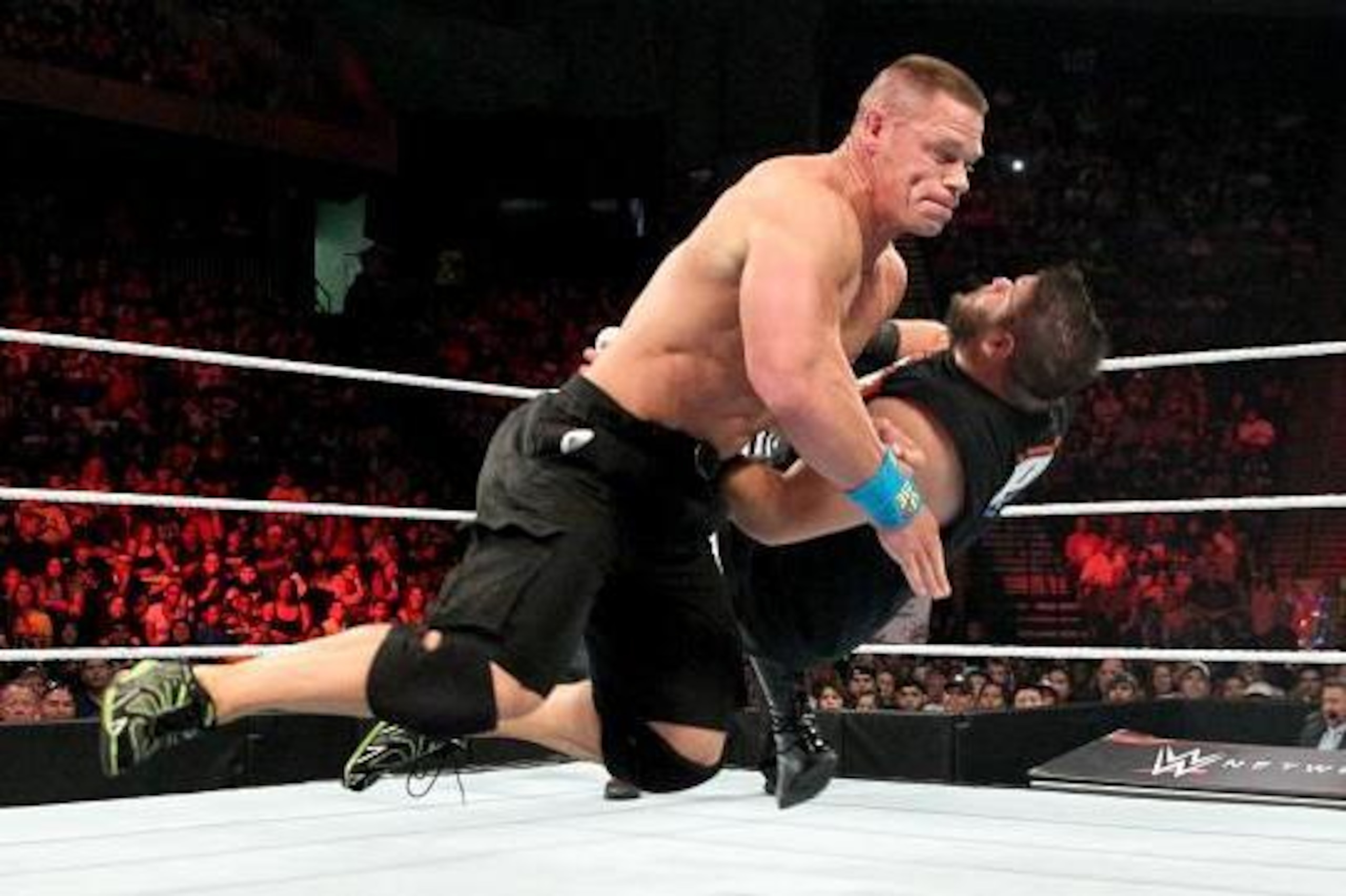 John Cena drops Kevin Owens with a shoulder block.