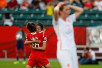 EDMONTON, AB - JUNE 11: Wang Lisi #21 hugs teammate Lou Jiahui #16 of China after she scored the game winning goal while Merel Van Dongen #15 of Netherlands walks away during the FIFA Women's World Cup Canada Group A match between China and Netherlands at
