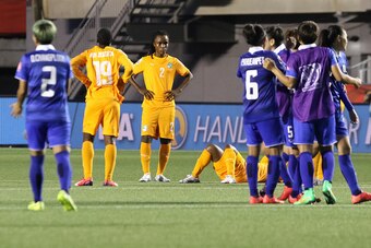 OTTAWA, ON - JUNE 11: Jessica Aby #19 and Fatou Coulibaly #2 of Cote d'Ivoire look on as Thailand celebrates their win after the FIFA Women's World Cup Canada 2015 Group B match between Cote d'Ivoire and Thailand at Lansdowne Stadium on June 11, 2015 in O