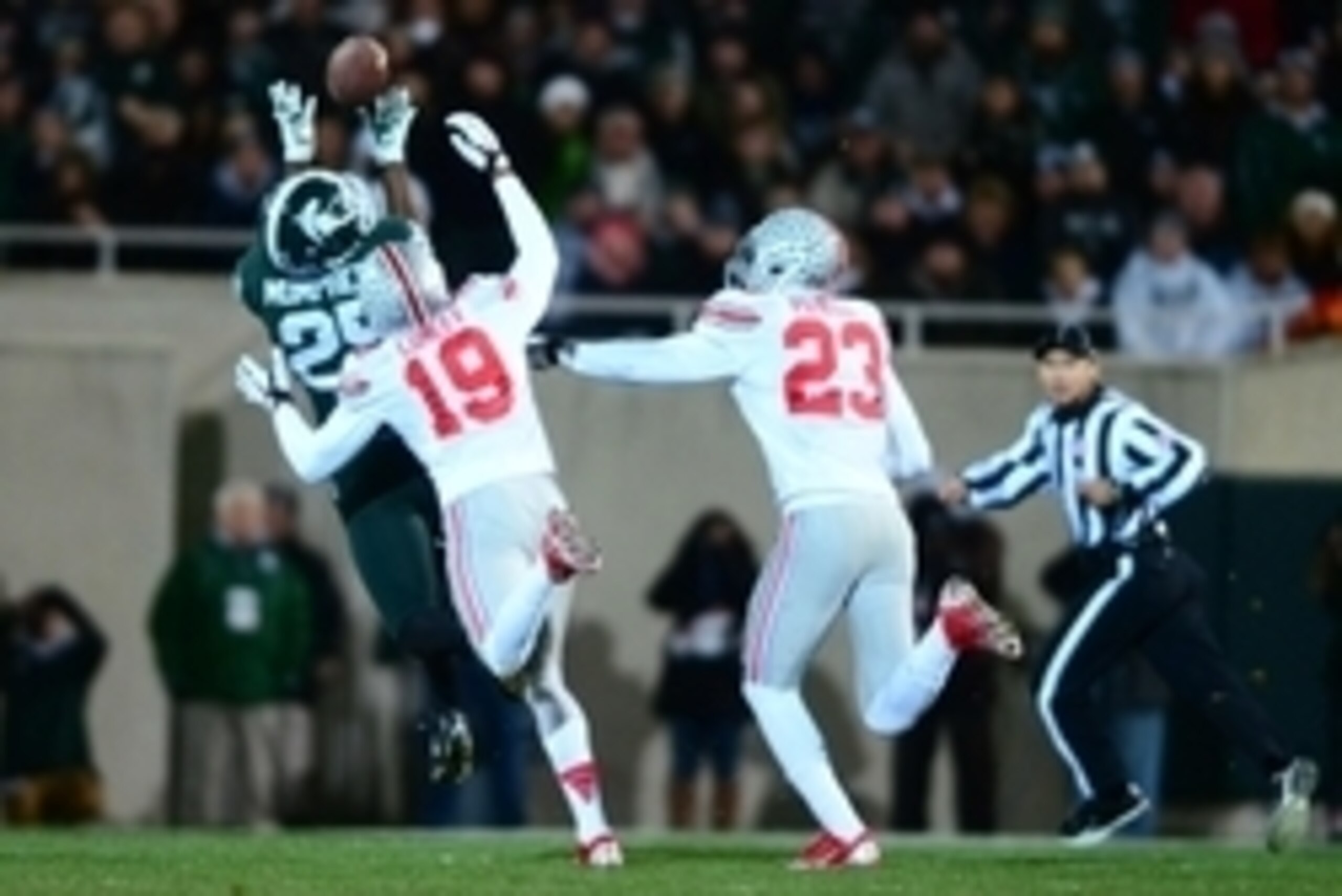 Nov 8, 2014; East Lansing, MI, USA; Michigan State Spartans wide receiver Keith Mumphery (25) makes a catch while being defended by Ohio State Buckeyes cornerback Gareon Conley (19) and safety Tyvis Powell (23) during the first quarter at Spartan Stadium.