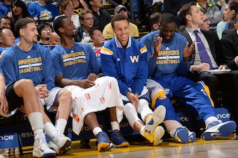 OAKLAND, CA - APRIL 15: Klay Thompson #11, Harrison Barnes #40, Stephen Curry #30, and Draymond Green #23 of the Golden State Warriors sit on the sideline during a game against the Denver Nuggets on April 15, 2015 at Oracle Arena in Oakland, California. N