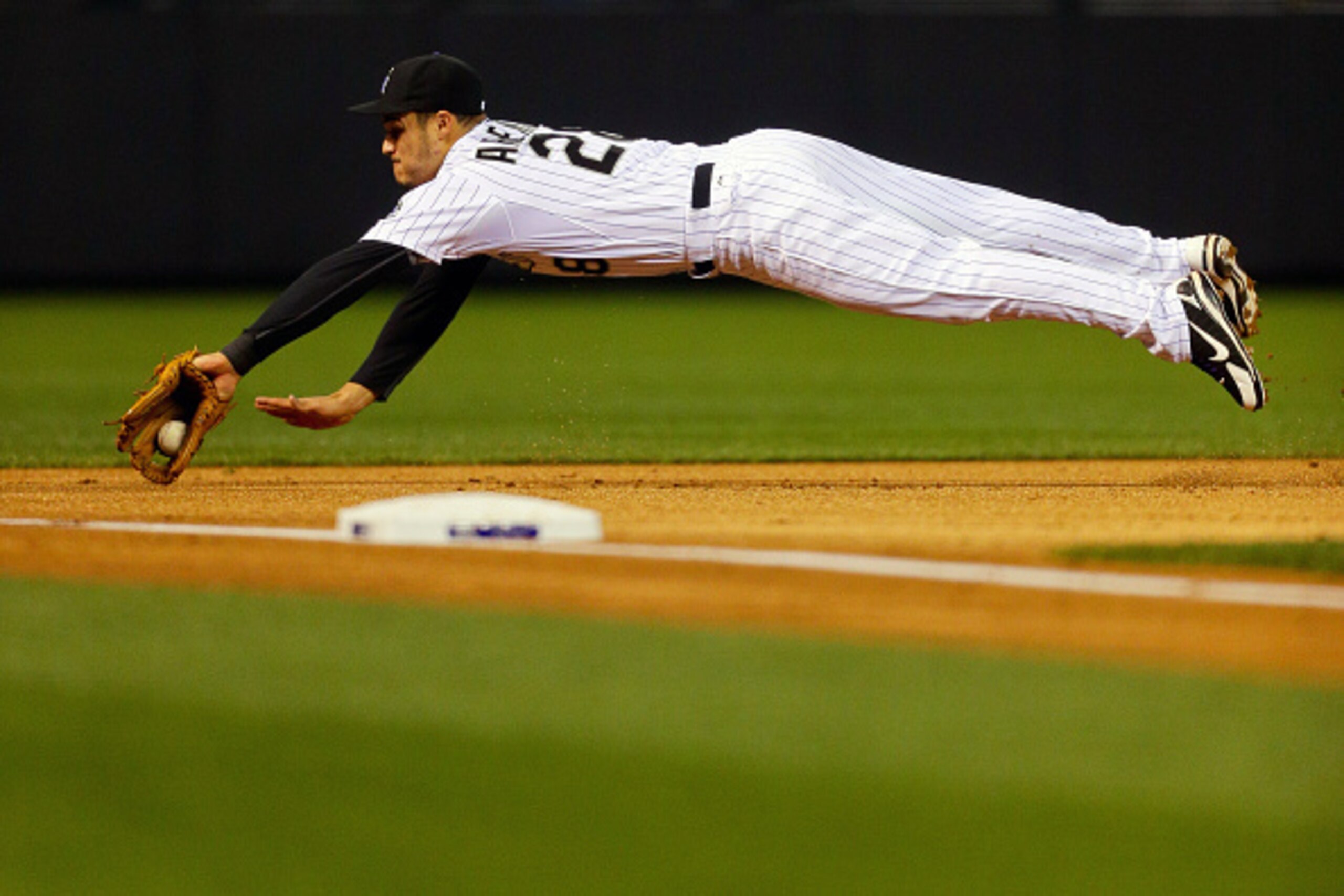 DENVER, CO - MAY 8:  Third baseman Nolan Arenado #28 of the Colorado Rockies dives on an infield hit by Alex Guerrero (not pictured) of the Los Angeles Dodgers during the first inning at Coors Field on May 8, 2015 in Denver, Colorado. (Photo by Justin Edm