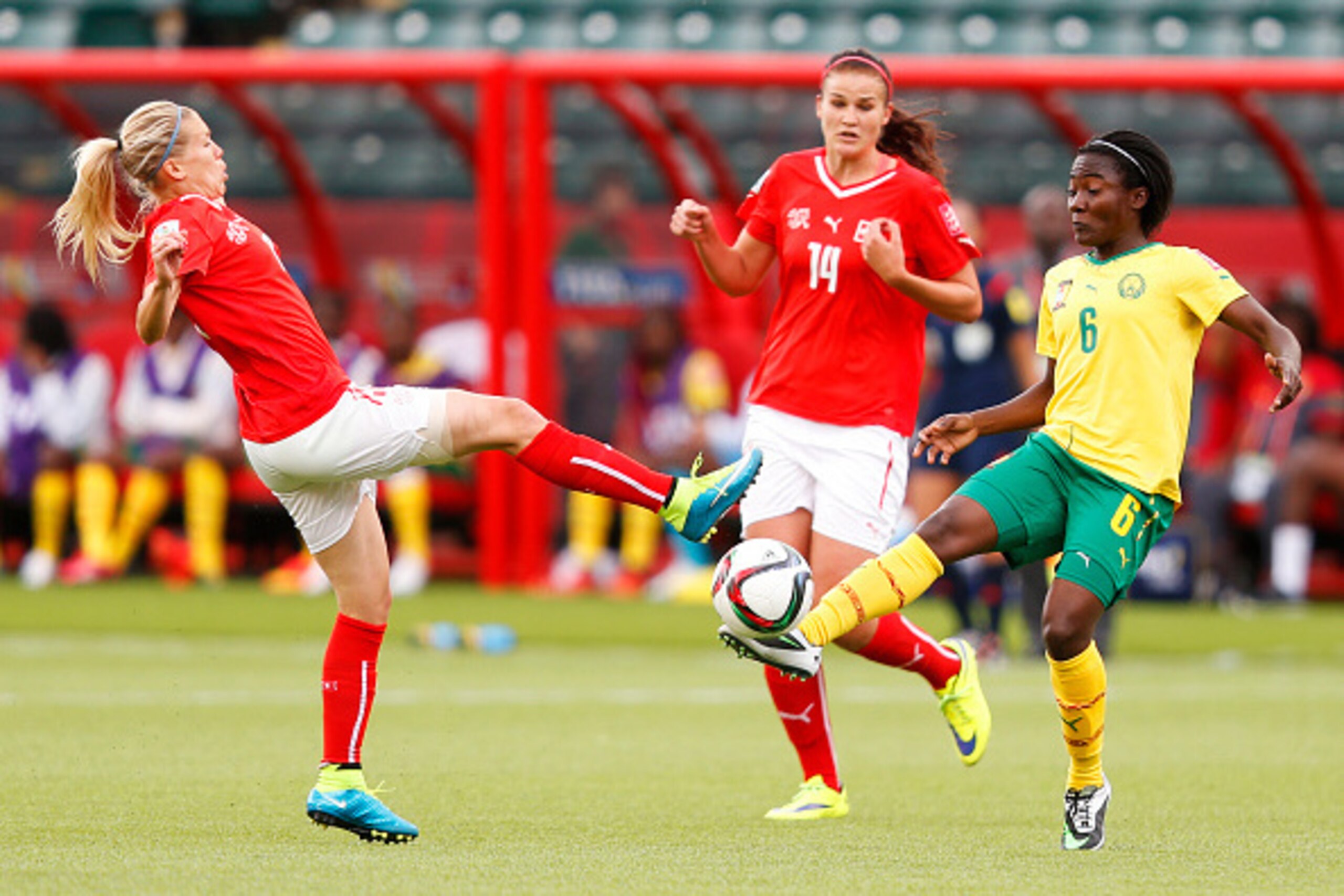 EDMONTON, AB - JUNE 16: Lara Dickenmann #11 of Switzerland and Francine Zouga #6 of Cameroon kick the ball in front of Rahel Kiwic #14 during the FIFA Women's World Cup Canada Group C match between Switzerland and Cameroon at Commonwealth Stadium on June 