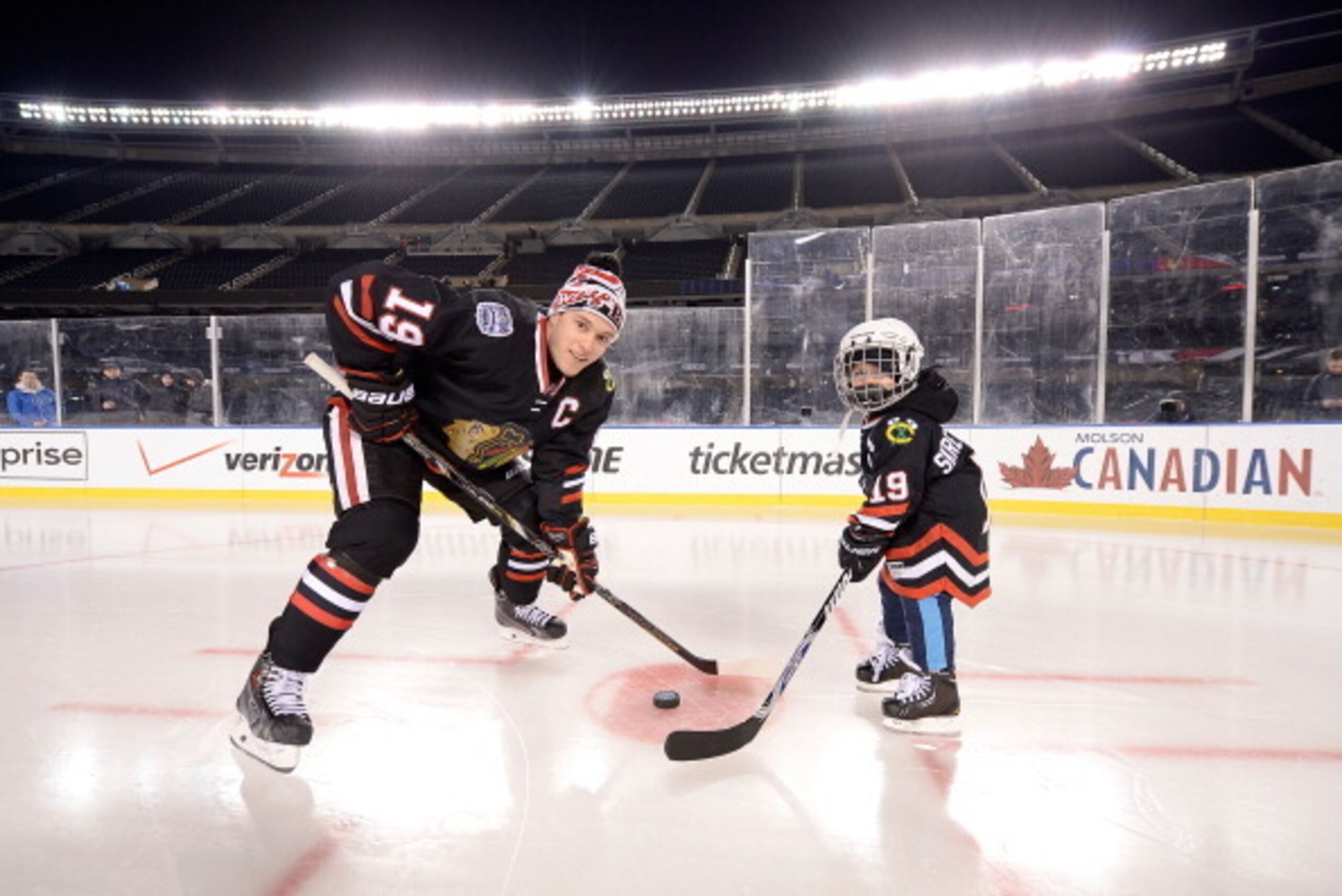 CHICAGO, IL - FEBRUARY 28:  (EDITORIAL USE ONLY) Jonathan Toews #19 of the Chicago Blackhawks takes a faceoff with four-year-old Make-A-Wish guest Nicholas Skretkowski prior to the 2014 NHL Stadium Series practice day at Soldier Field on February 28, 2014