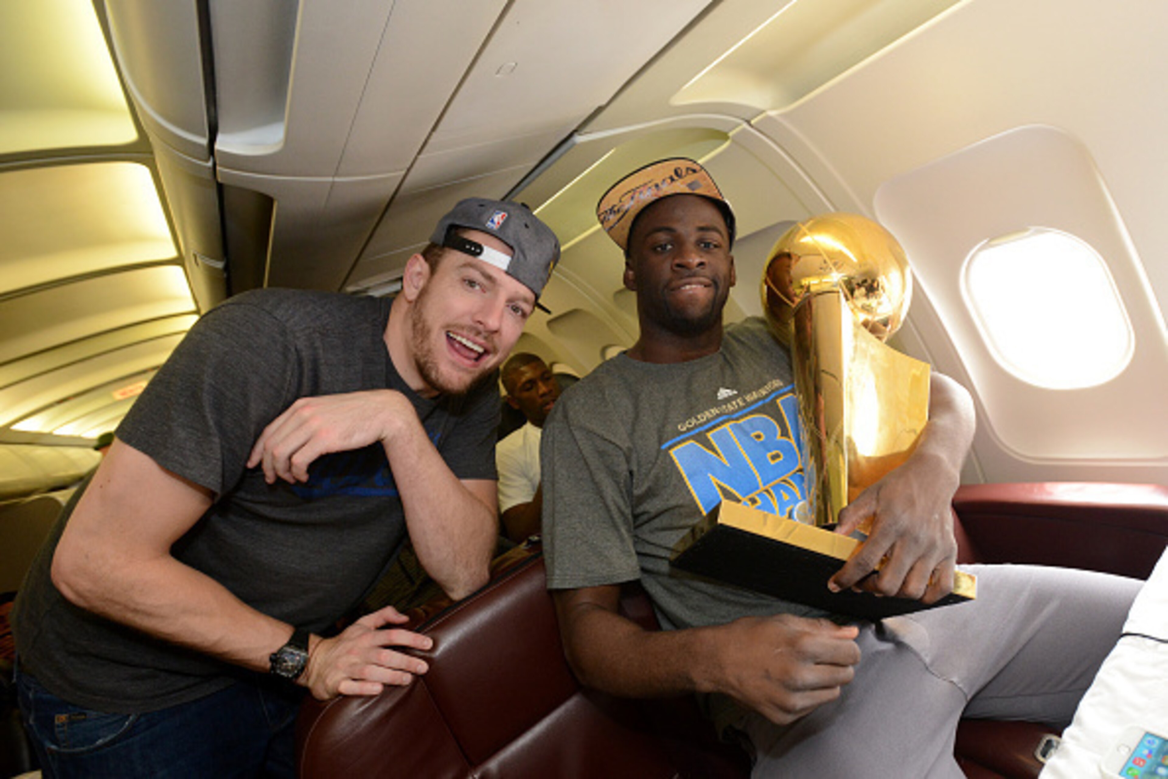 OAKLAND, CA - JUNE 17:  David Lee #10 and Draymond Green #23 of the Golden State Warriors holds the NBA trophy on the plane as the team travels home from Cleveland after winning the 2015 NBA Finals on June 17, 2015 in Oakland, California. NOTE TO USER: Us