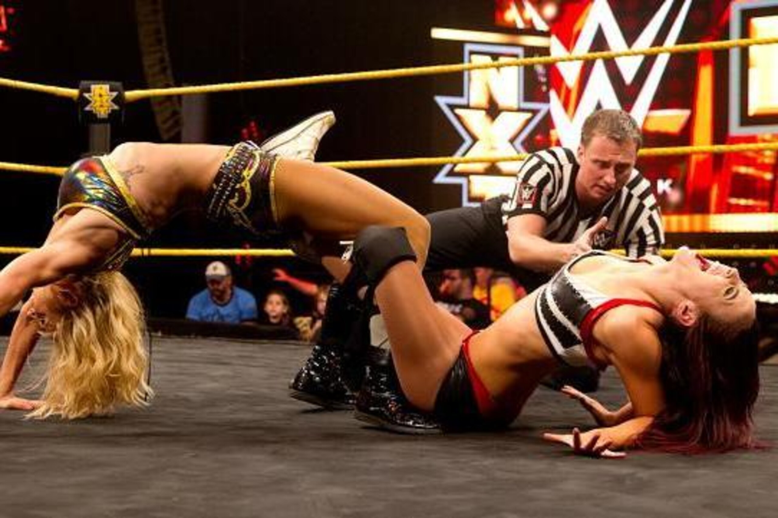 Charlotte clamps a figure-four leglock on Cassie.