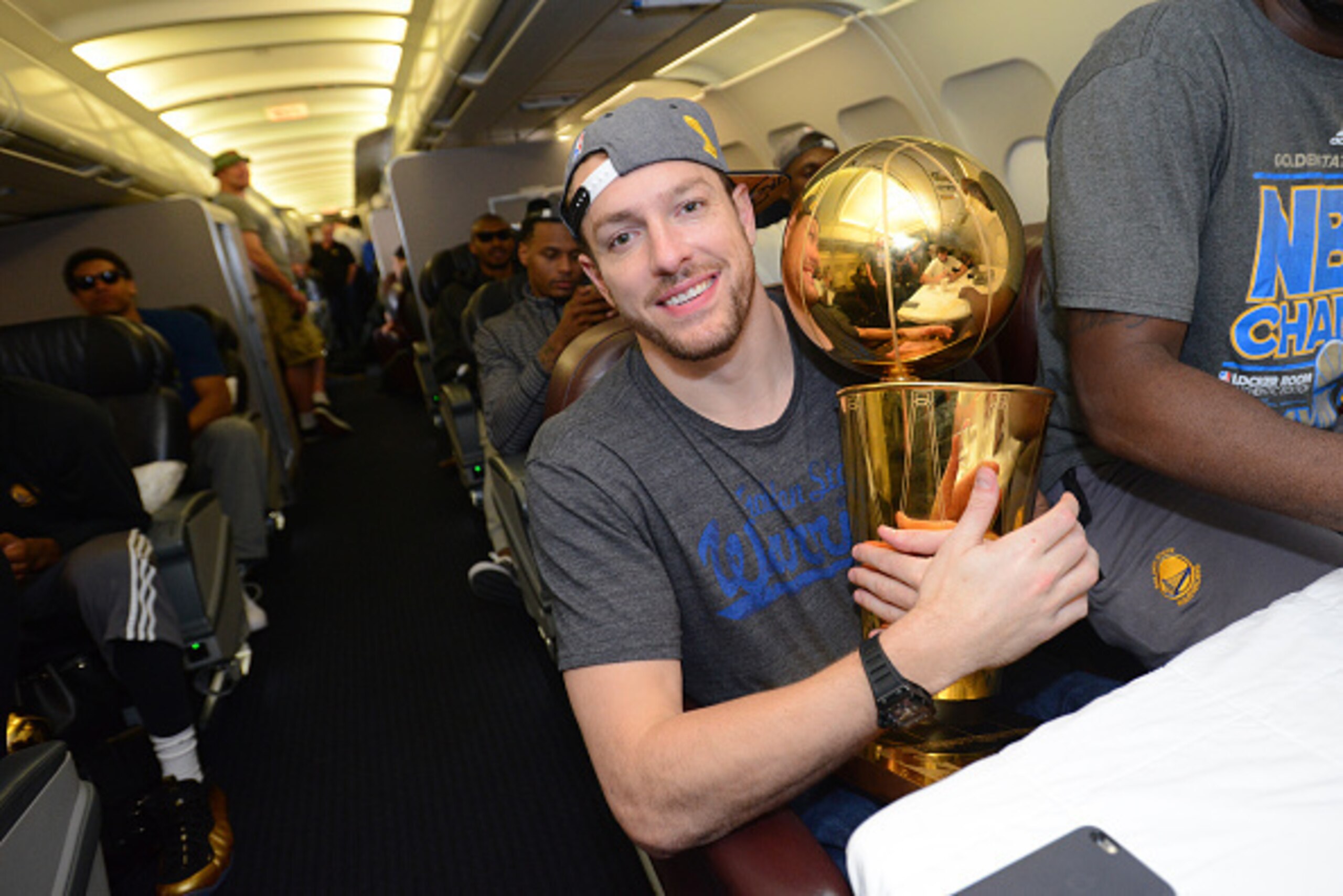 OAKLAND, CA - JUNE 17:  David Lee #10 of the Golden State Warriors holds the NBA trophy on the plane as the team travels home from Cleveland after winning the 2015 NBA Finals on June 17, 2015 in Oakland, California. NOTE TO USER: User expressly acknowledg