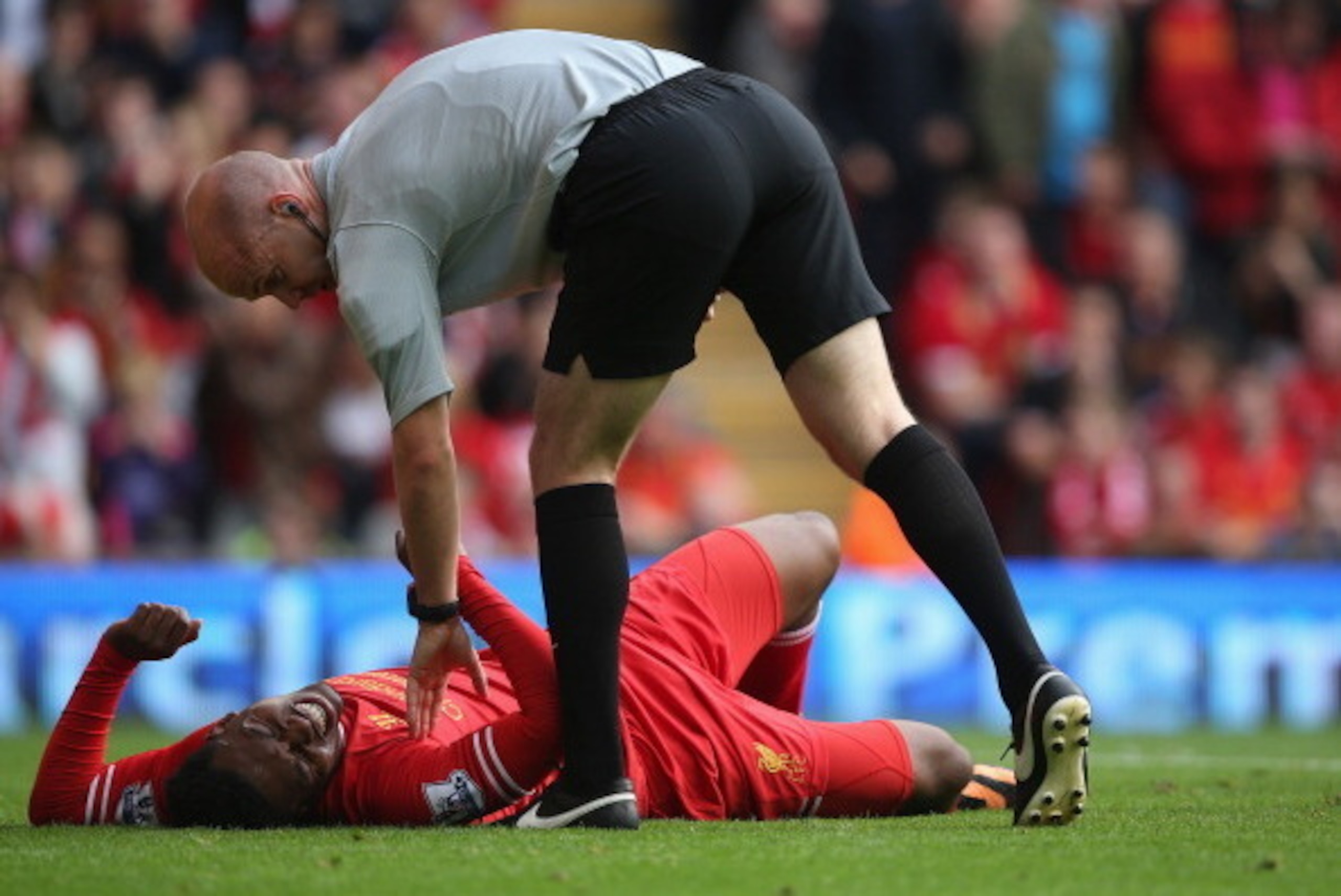 LIVERPOOL, ENGLAND - OCTOBER 05:  Daniel Sturridge of Liverpool lies injured and is checked by the referee Mr A Taylor during the Barclays Premier League match between Liverpool and Crystal Palace at Anfield on October 5, 2013 in Liverpool, England.  (Pho