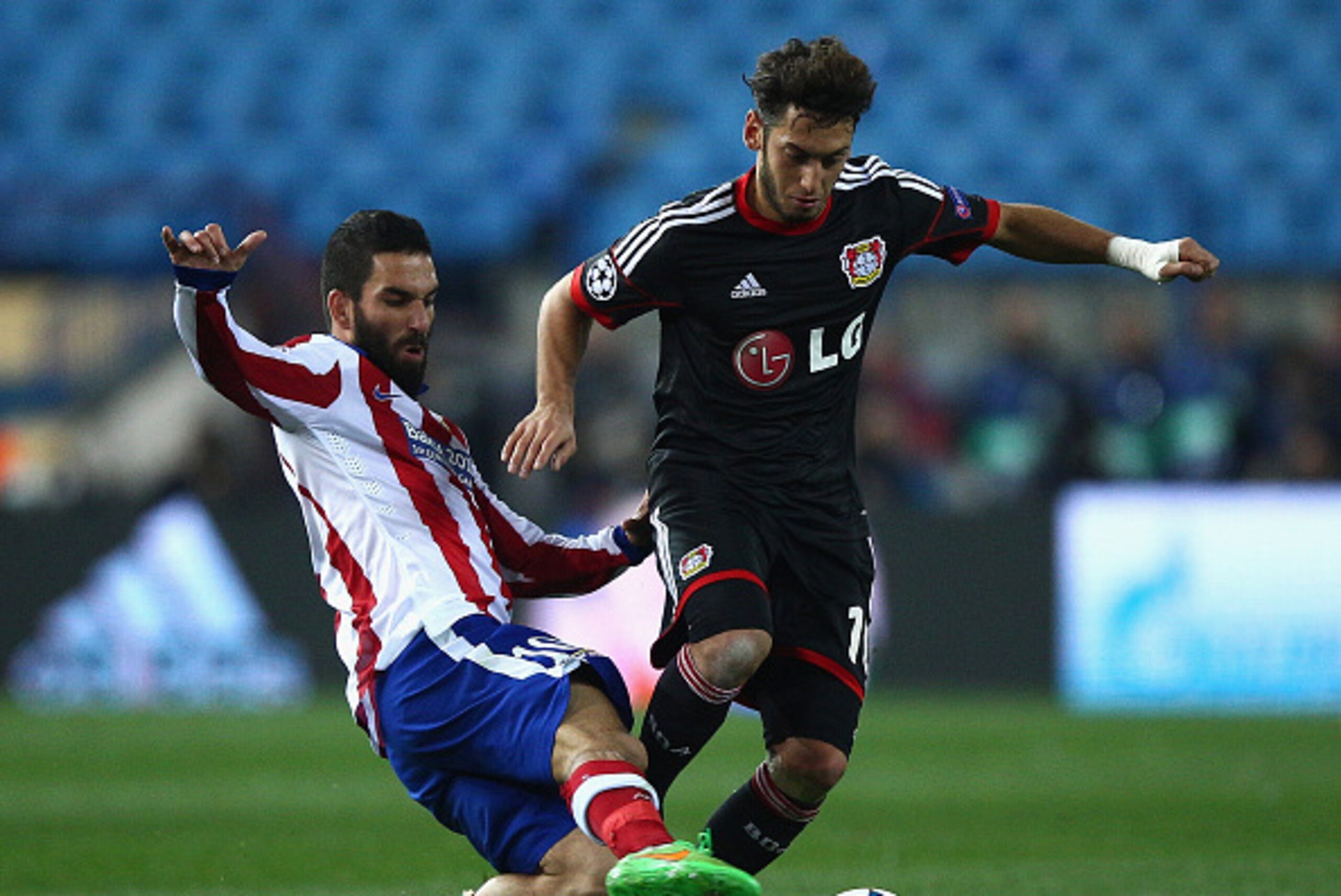 MADRID, SPAIN - MARCH 17:  Arda Turan of Atletico Madrid tackles Hakan Calhanoglu of Bayer Leverkusen during the UEFA Champions League round of 16 match between Club Atletico de Madrid and Bayer 04 Leverkusen at Vicente Calderon Stadium on March 17, 2015 