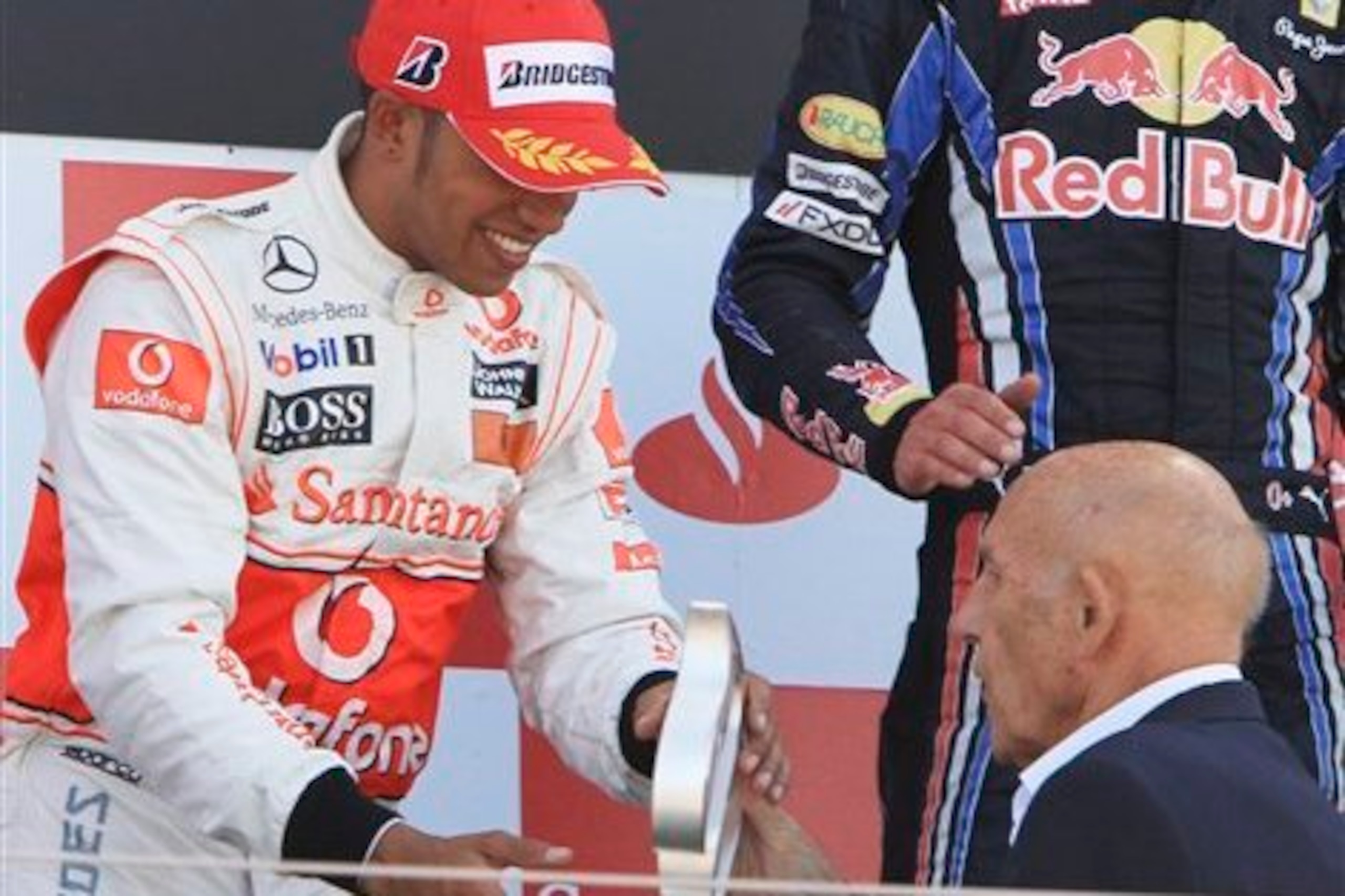 Moss hands Lewis Hamilton the second place trophy at the 2010 British Grand Prix.