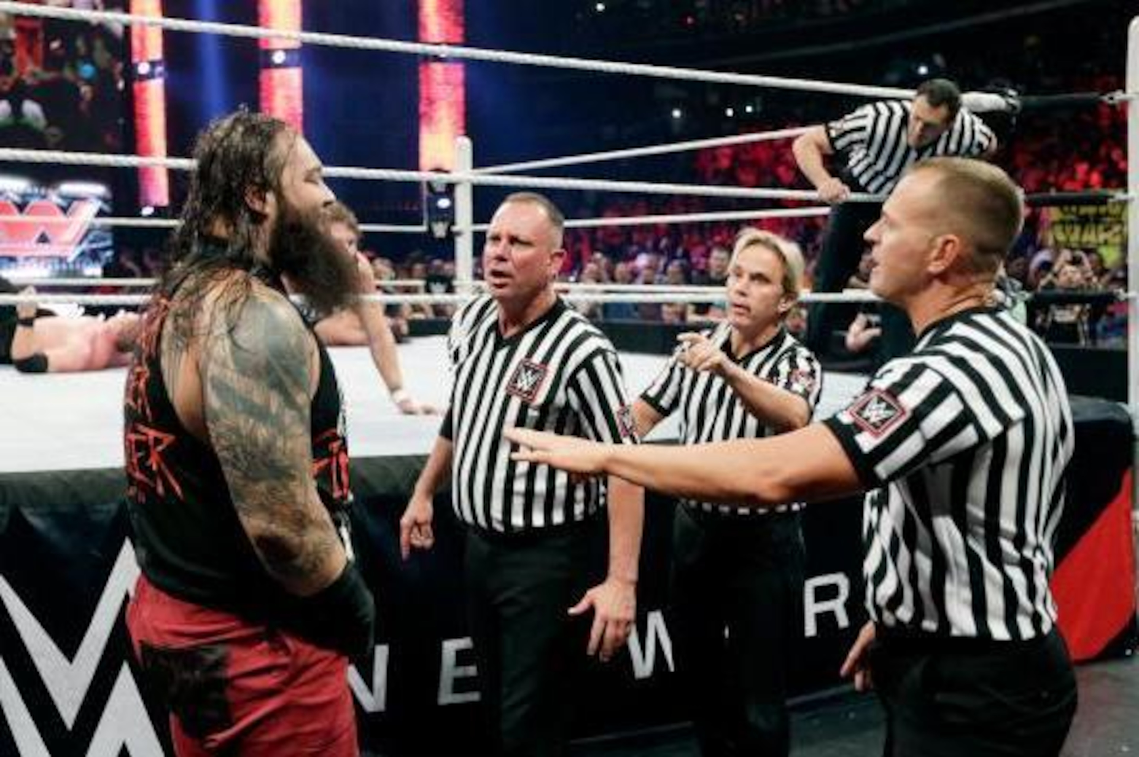 Referees look to keep Bray Wyatt away from Roman Reigns.