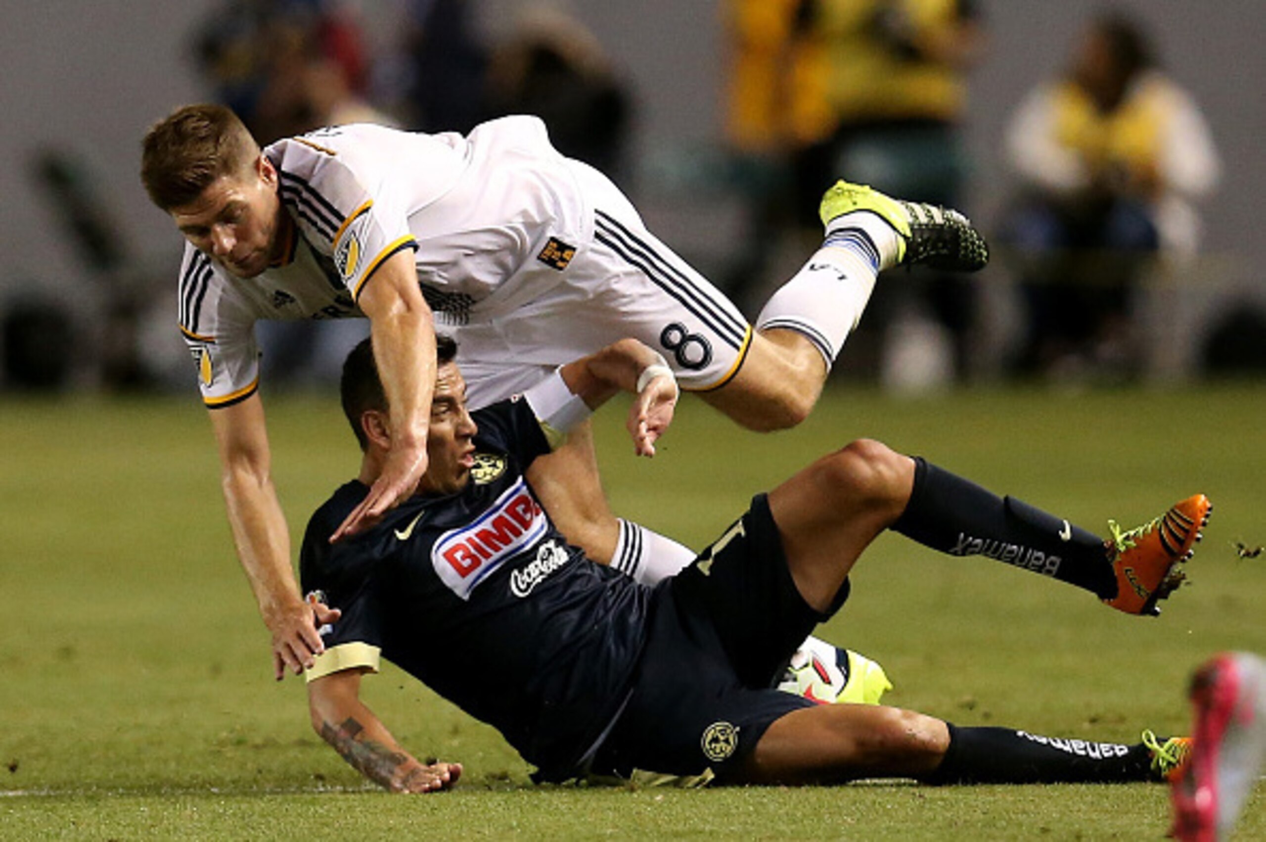 LOS ANGELES, CA - JULY 11:  Steven Gerrard #8 of the Los Angeles Galaxy tumbles over Rubens Sambueza #14 of Club America in the International Champions Cup 2015 at StubHub Center on July 11, 2015 in Los Angeles, California.  (Photo by Stephen Dunn/Getty I