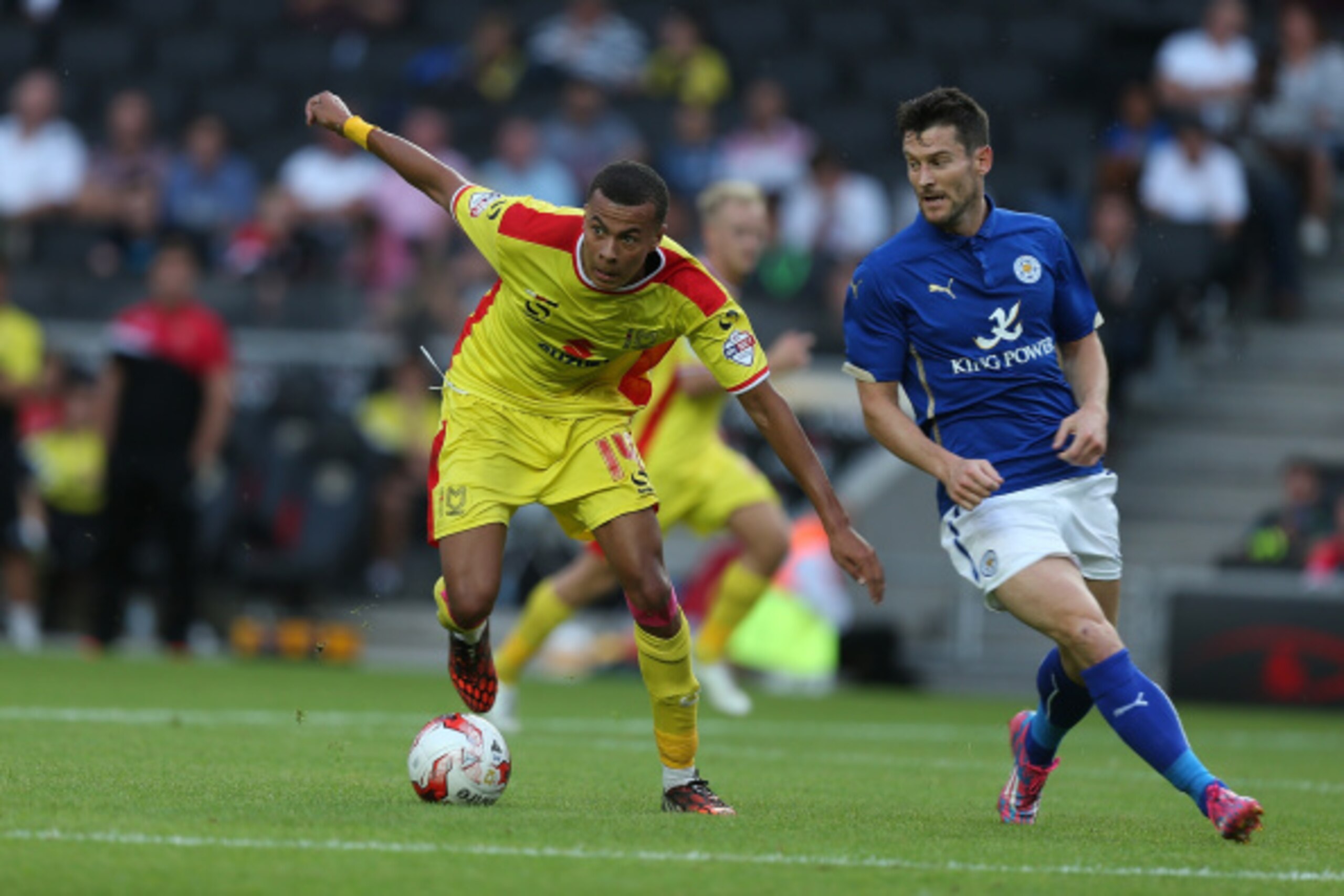 MILTON KEYNES, ENGLAND - AUGUST 04: Dele Alli of MK Dons looks to control the ball watched by David Nugent of Leicester City during the Pre-Season Friendly match between MK Dons and Leicester City  at Stadium mk on August 4, 2014 in Milton Keynes, England