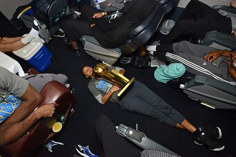 OAKLAND, CA - JUNE 17:  Stephen Curry #30 of the Golden State Warriors holds the NBA trophy on the plane floor as the team travels home from Cleveland after winning the 2015 NBA Finals on June 17, 2015 in Oakland, California. NOTE TO USER: User expressly 