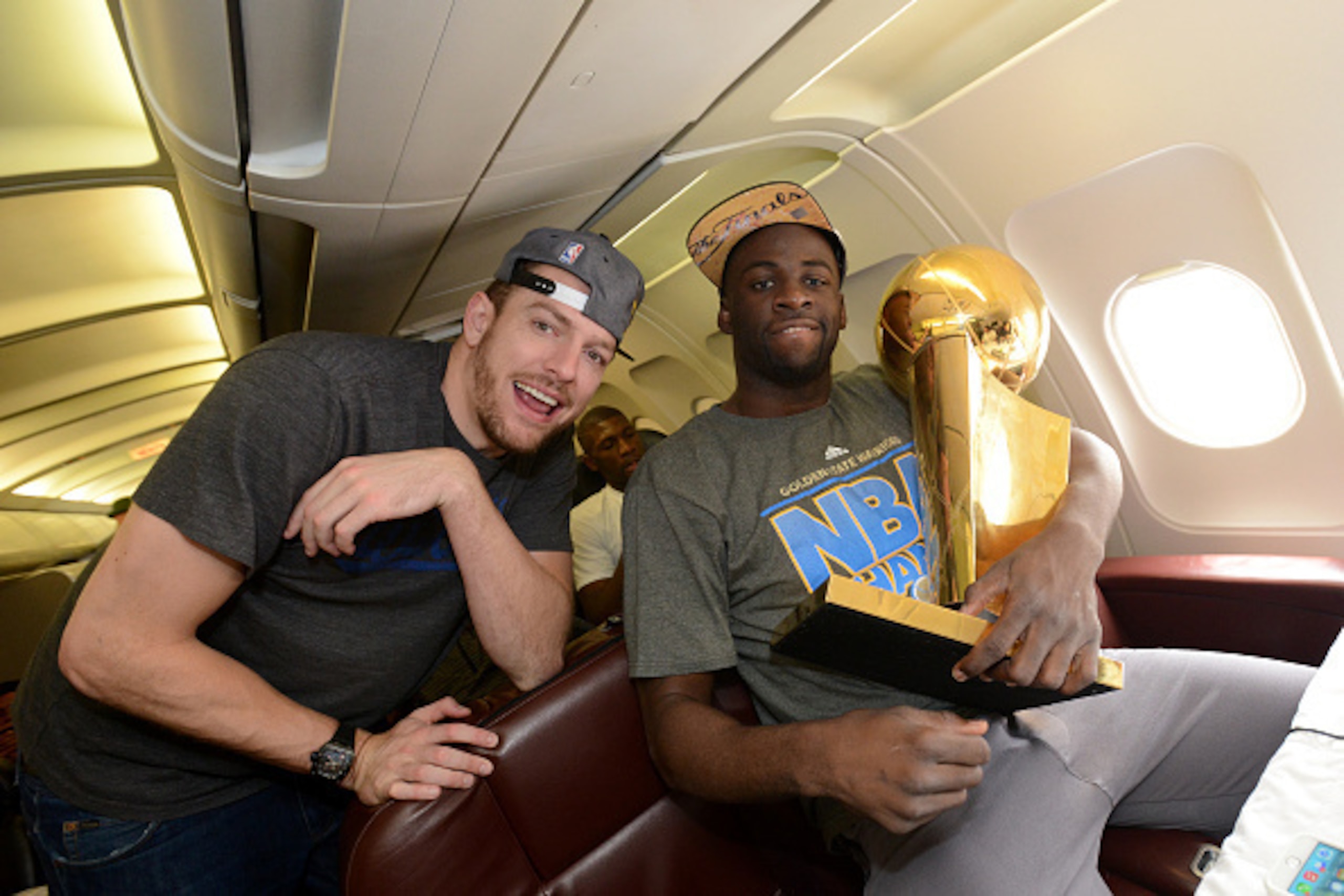 OAKLAND, CA - JUNE 17:  David Lee #10 and Draymond Green #23 of the Golden State Warriors holds the NBA trophy on the plane as the team travels home from Cleveland after winning the 2015 NBA Finals on June 17, 2015 in Oakland, California. NOTE TO USER: Us