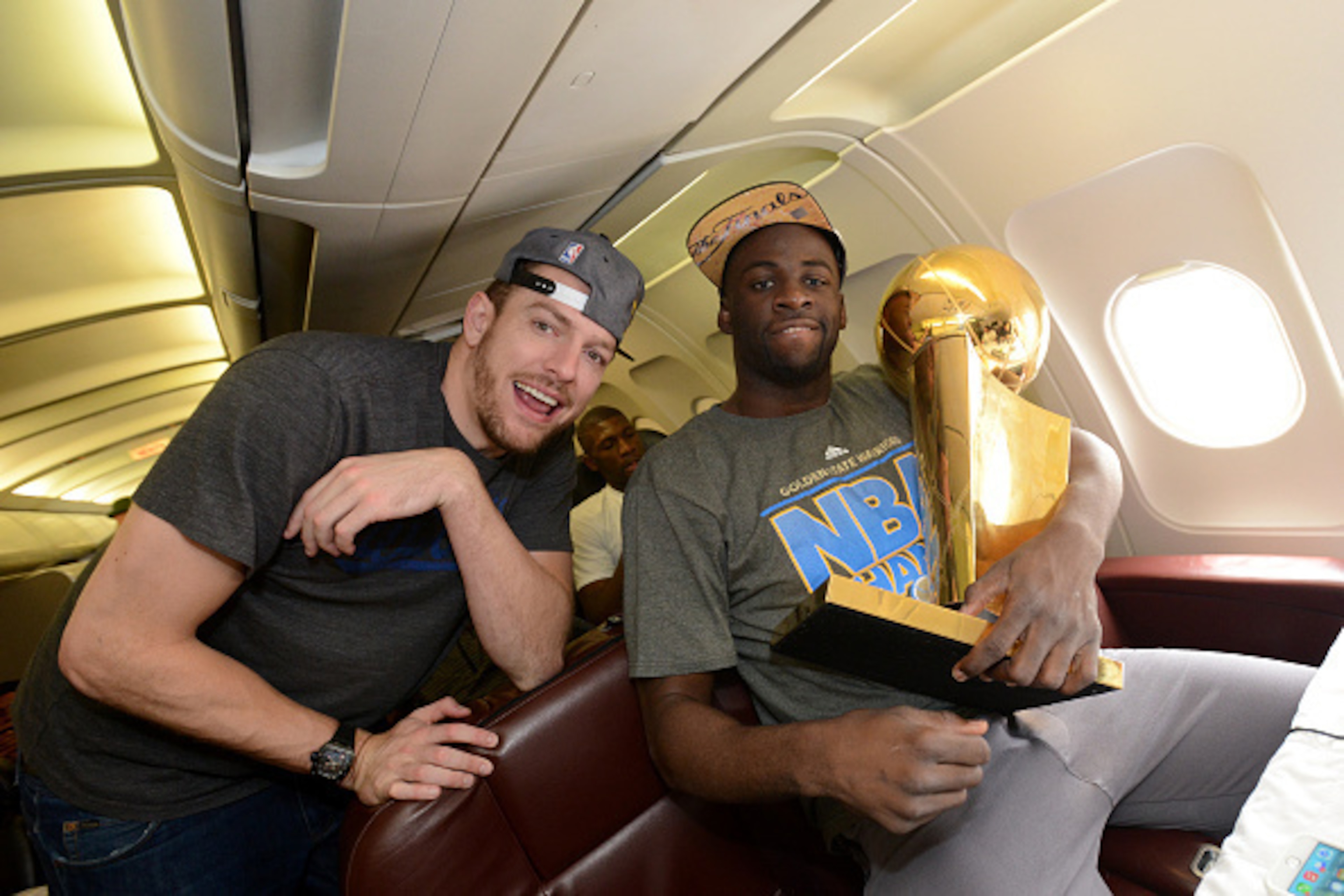 OAKLAND, CA - JUNE 17:  David Lee #10 and Draymond Green #23 of the Golden State Warriors holds the NBA trophy on the plane as the team travels home from Cleveland after winning the 2015 NBA Finals on June 17, 2015 in Oakland, California. NOTE TO USER: Us