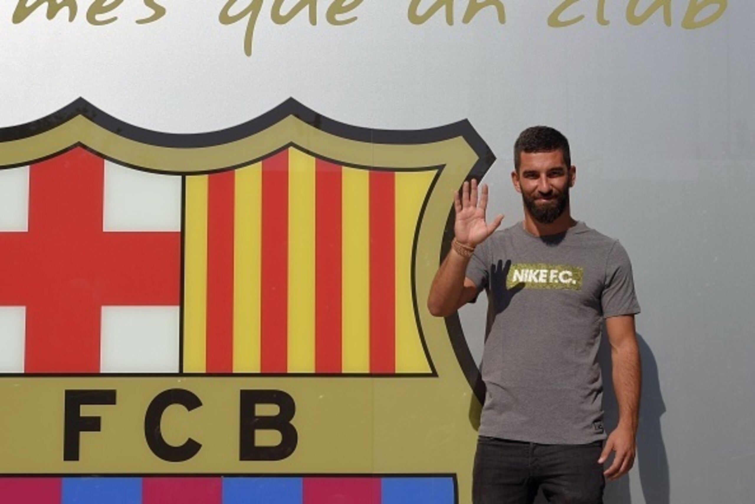 Barcelona's new player Turkish Arda Turan waves as he poses outside the Camp Nou stadium in Barcelona, prior to signing his new contract with the Catalan club, on July 9, 2015. Barcelona announced on July 6, 2015 the signing of the 28-year-old Turkish int