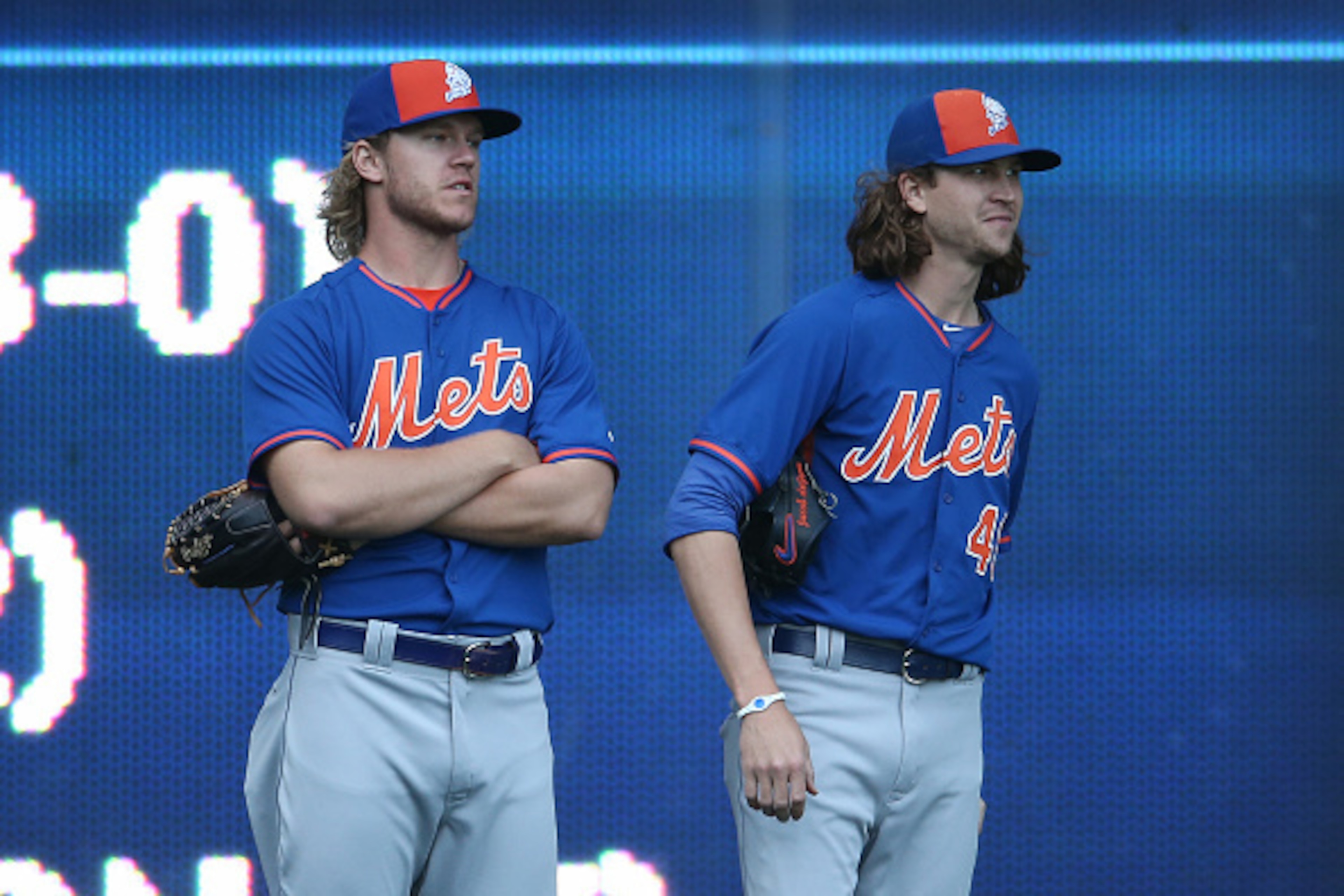 TORONTO, CANADA - JUNE 17: Noah Syndergaard #34 and Jacob deGrom #48 of the New York Mets look on from the outfield during batting practice before the start of the MLB game against the Toronto Blue Jays on June 17, 2015 at Rogers Centre in Toronto, Ontari
