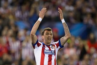 Atletico Madrid's Croatian forward Mario Mandzukic raises his arms during the UEFA Champions League quarter final football match Atletico de Madrid vs Real Madrid CF at the Vicente Calderon stadium in Madrid on April 14, 2015.  AFP PHOTO / DANI POZO      