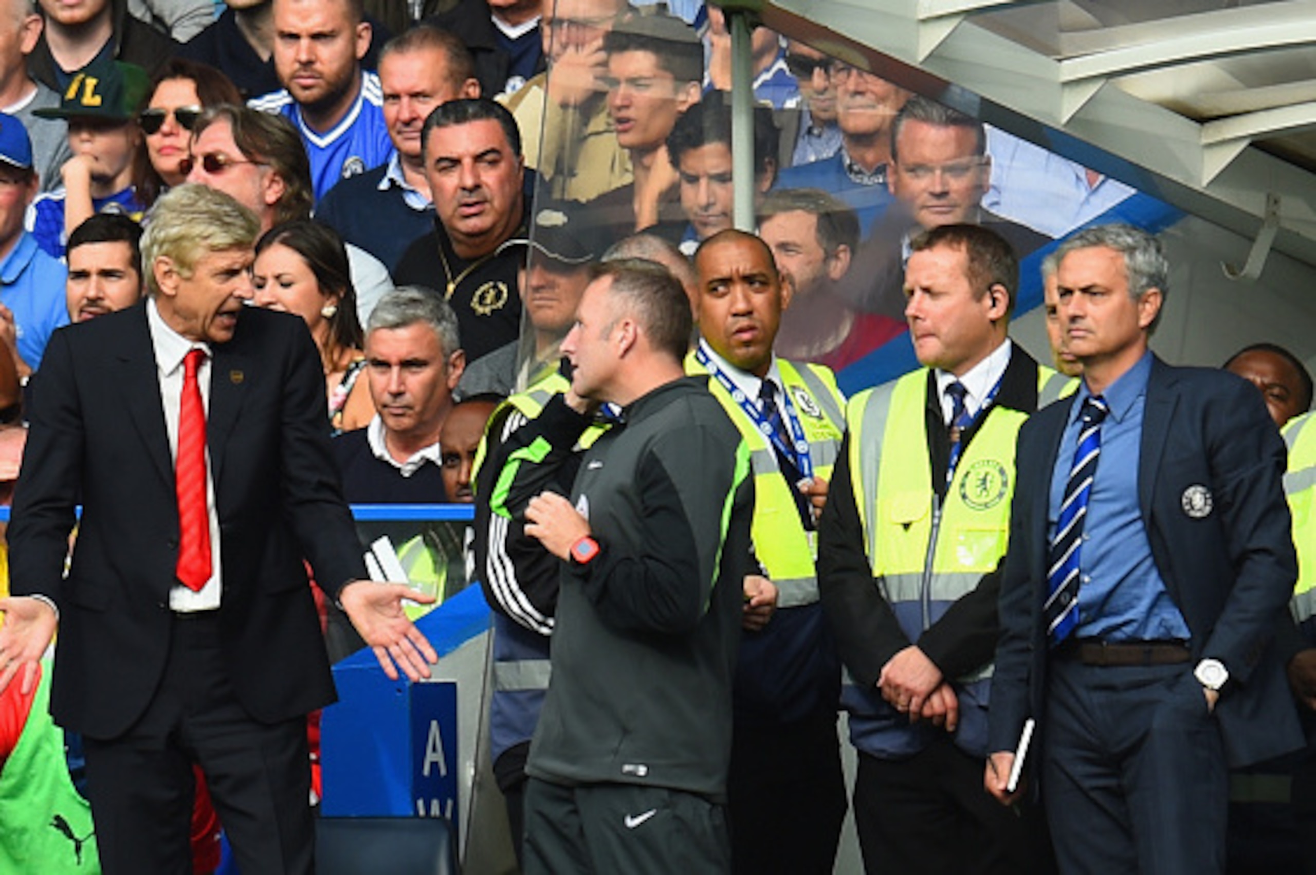 LONDON, ENGLAND - OCTOBER 05:  Arsene Wenger, manager of Arsenal speaks to fourth official Jonathan Moss as Jose Mourinho manager of Chelsea looks on during the Barclays Premier League match between Chelsea and Arsenal at Stamford Bridge on October 4, 201