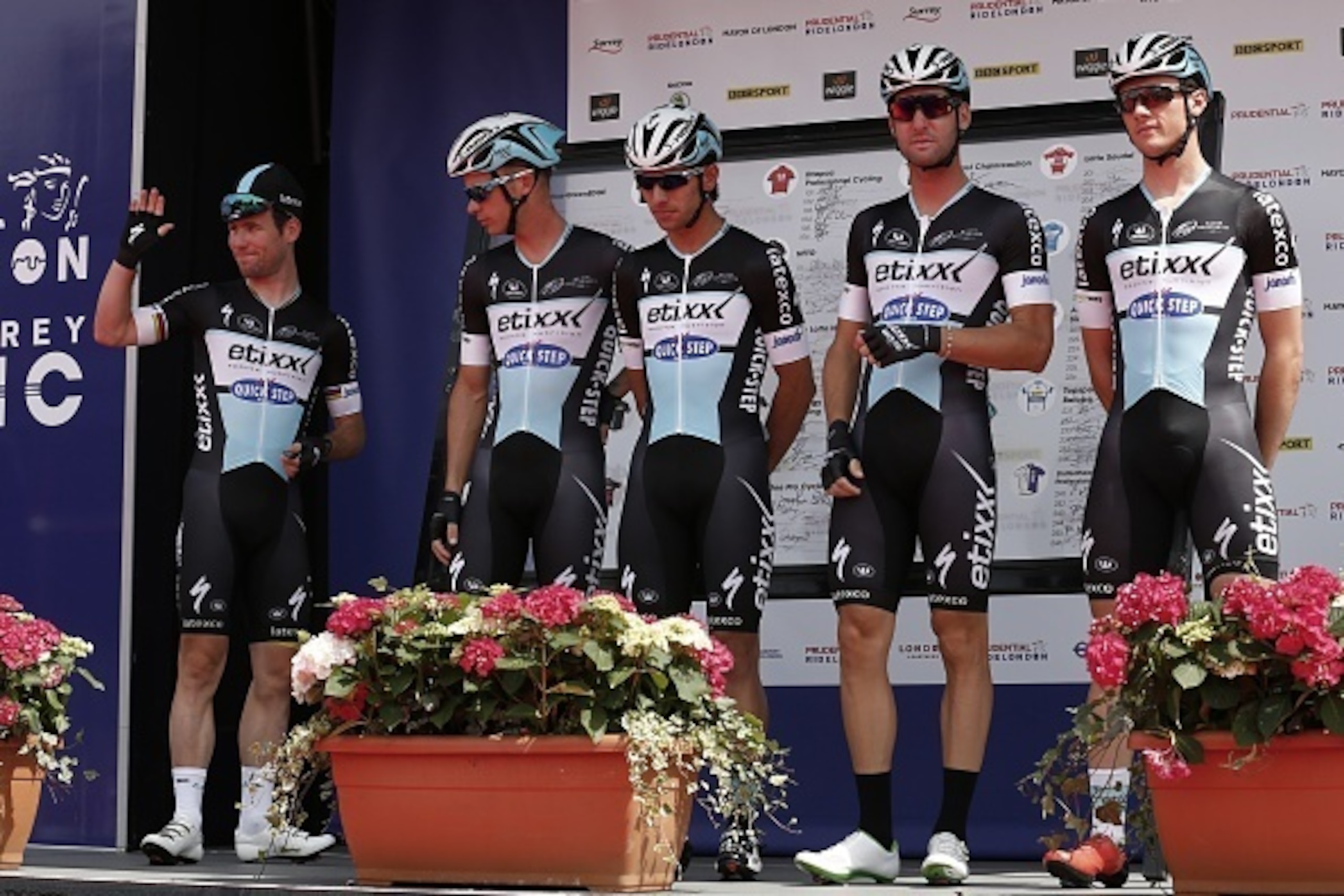 British cyclist Mark Cavendish (L) waves as his Etixx-Quick Step teammates pose at the signing on event ahead of the Ride London - Surrey Classic road cycle race in central London on August 2, 2015. AFP PHOTO / JUSTIN TALLIS        (Photo credit should re