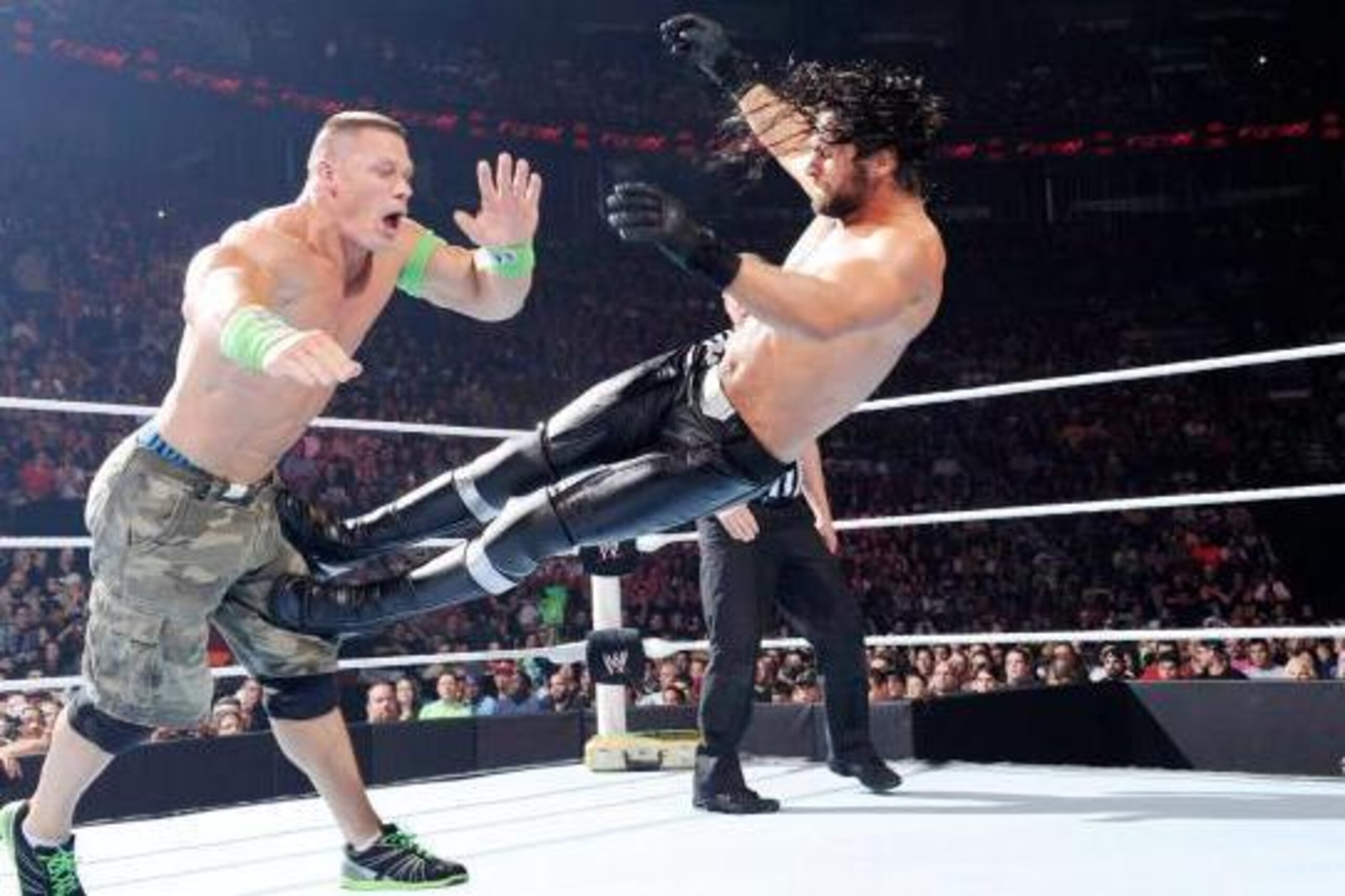 Seth Rollins takes out John Cena at the knee.