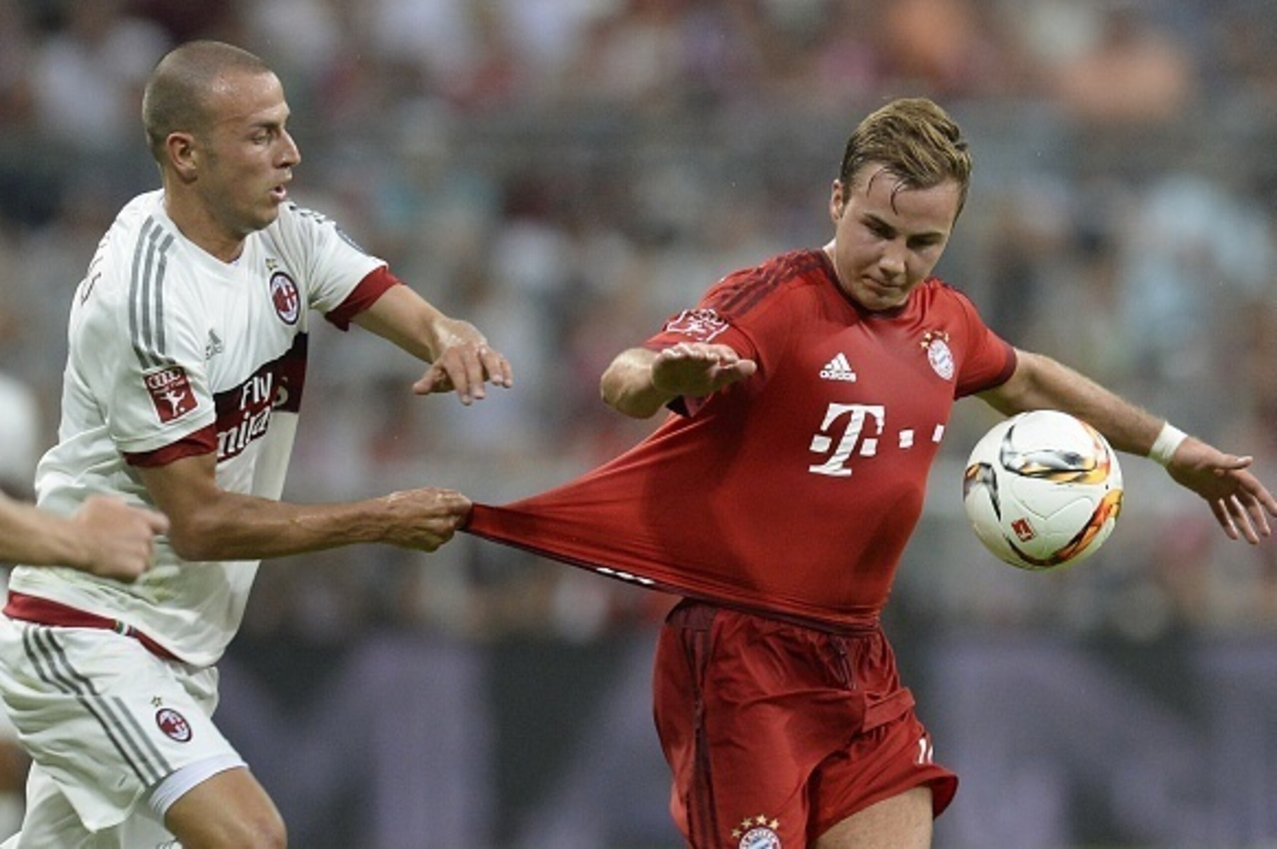 AC Milan's defender Luca Antonelli (L) pulls Bayern Munich's midfielder Mario Goetze's shirt during the Audi Cup football match FC Bayern Munich vs AC Milan in Munich, southern Germany, on August 4, 2015. The Audi Cup football matches with Bayern Munich o