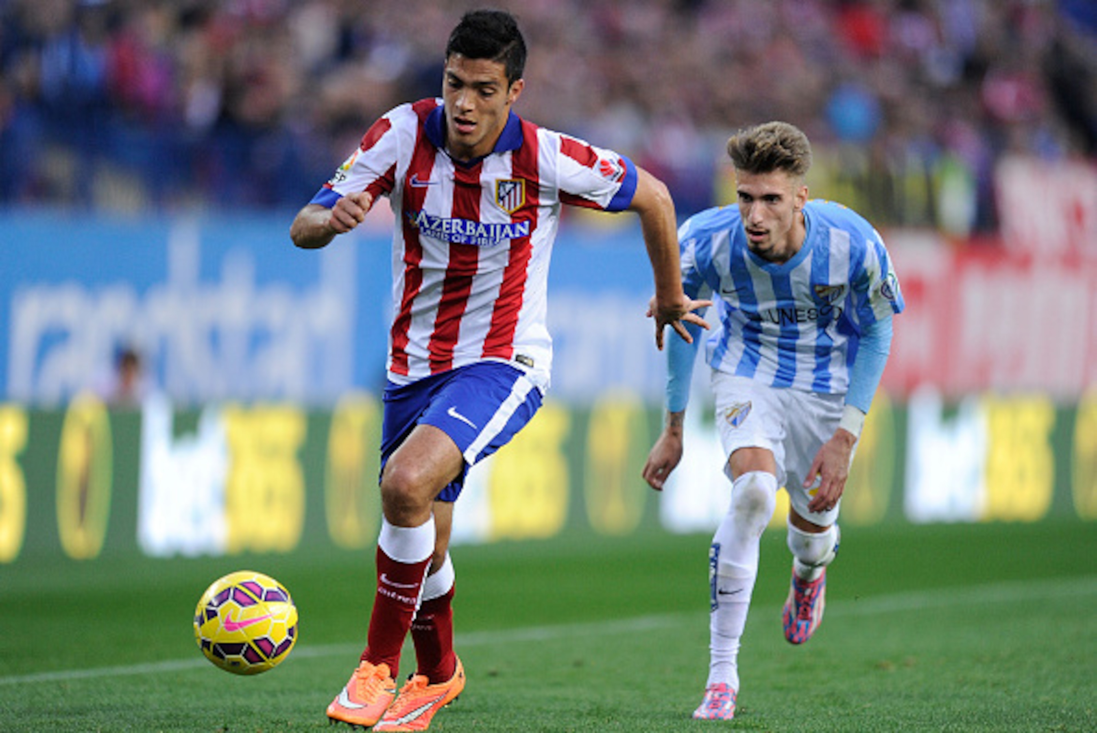 MADRID, SPAIN - NOVEMBER 22:  Raul Jimenez of Club Atletico de Madrid races past Samuel Castillejo of Malaga CF during the La Liga match between Club Atletico de Madrid and Malaga CF at Vicente Calderon Stadium on November 22, 2014 in Madrid, Spain.  (Pho
