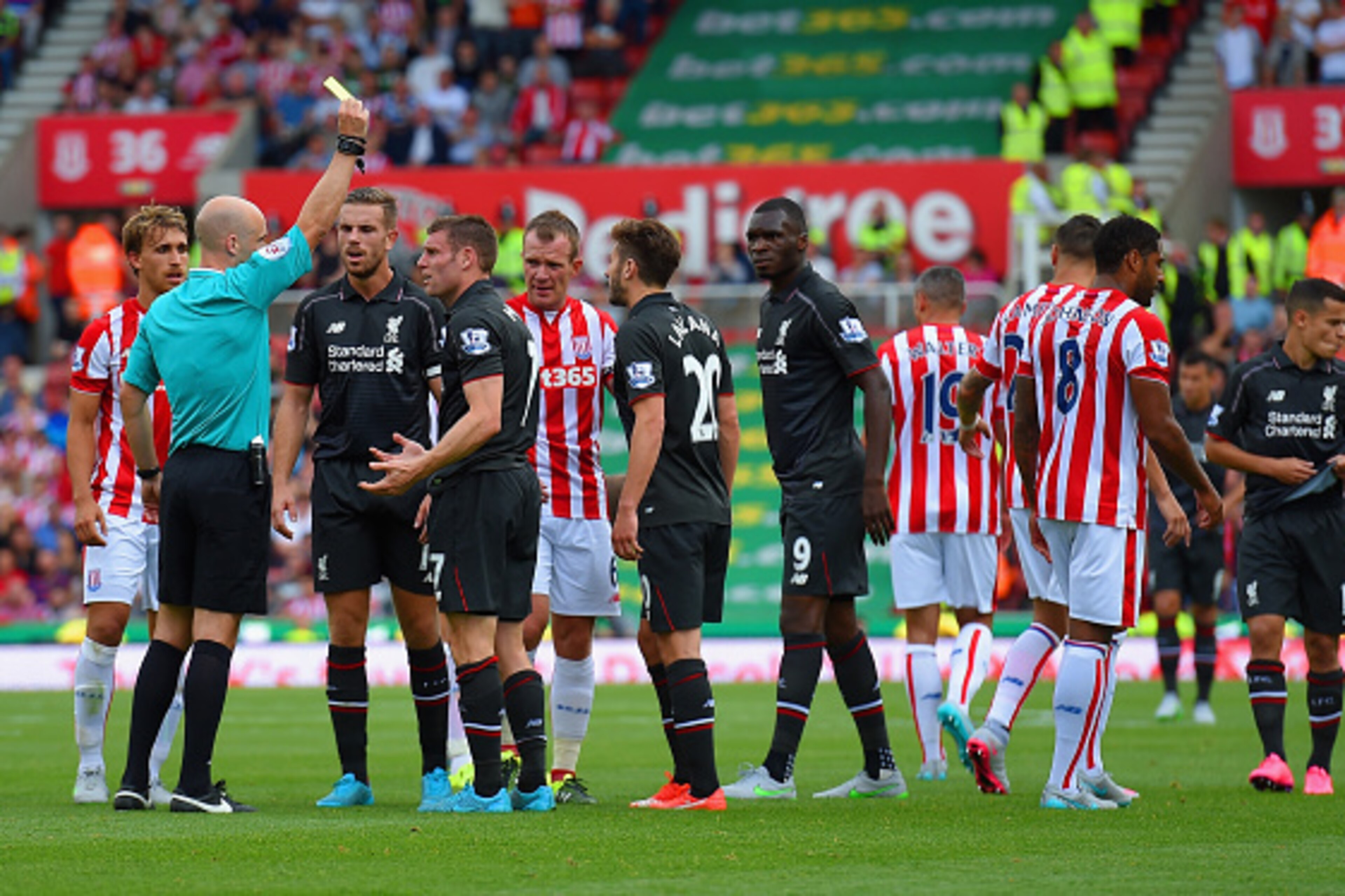 STOKE ON TRENT, ENGLAND - AUGUST 09: Referee Anthony Taylor shows James Milner of Liverpool a yellow card during the Barclays Premier League match between Stoke City and Liverpool at Brittania Stadium on August 9, 2015 in Stoke on Trent, England.  (Photo 